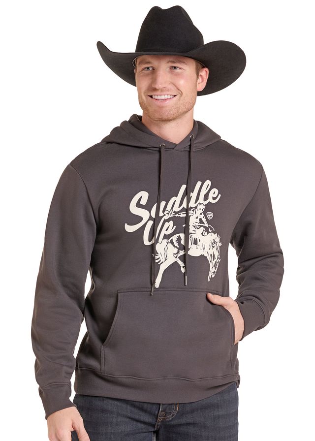 A man wearing a dark charcoal gray hoodie with a white graphic print that says 'Suddle Up' and shows a bucking horse rider. 