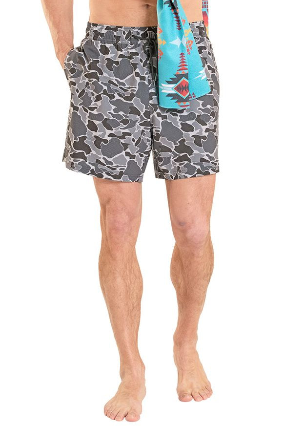 Man holding a colorful towel with camouflage shorts on a white background