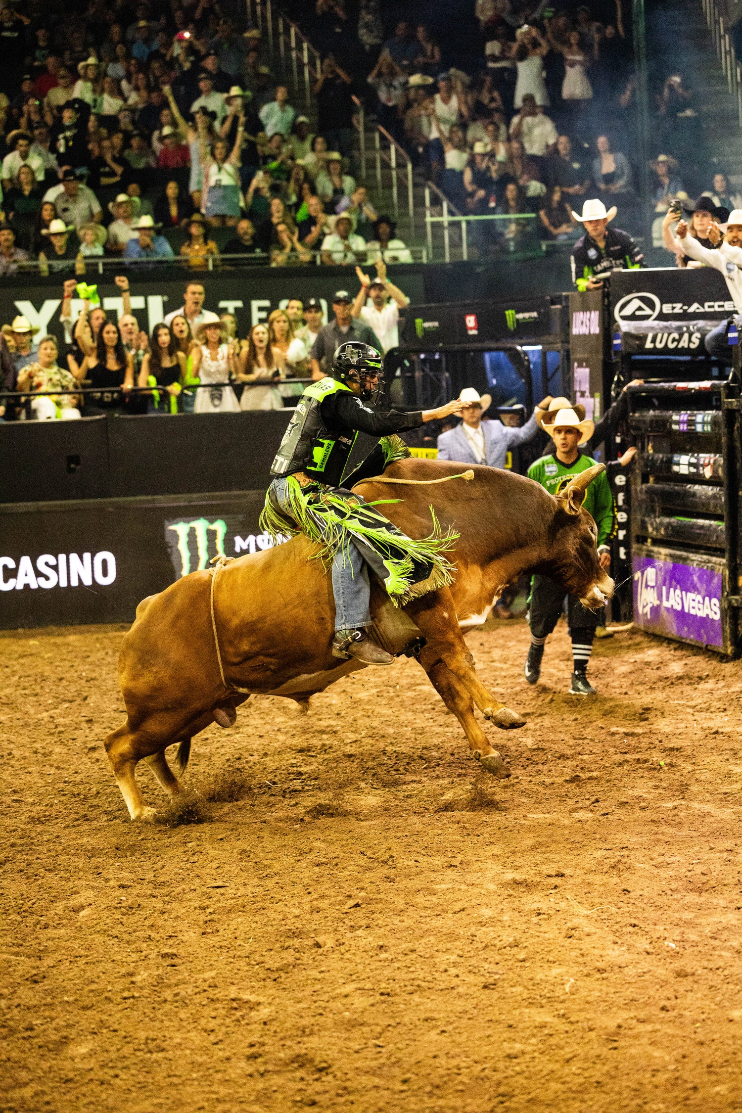 Bull rider in action at a rodeo event with a crowd watching.