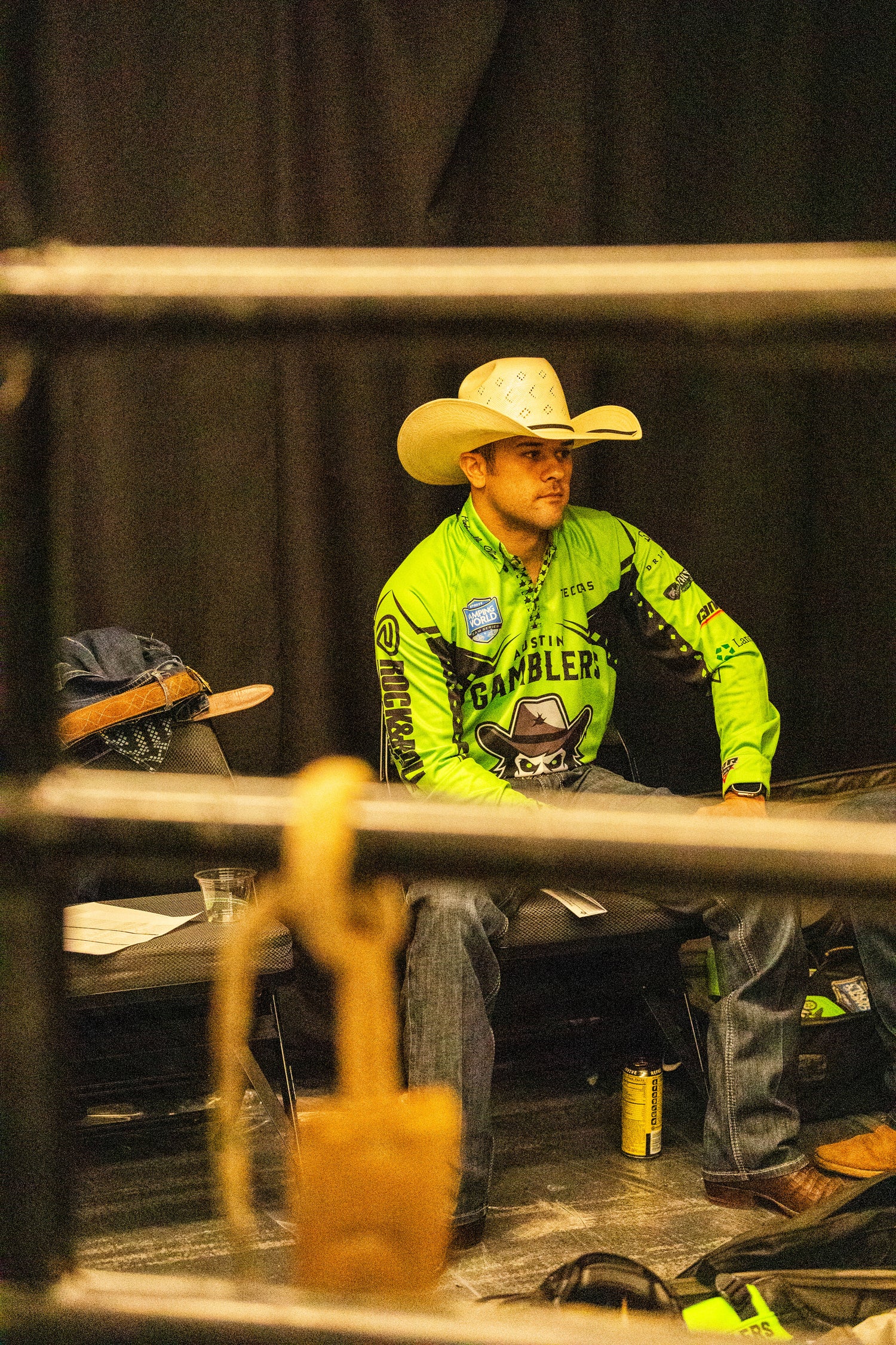 Cowboy in a green shirt and cowboy hat sitting on a bench with a blurred background