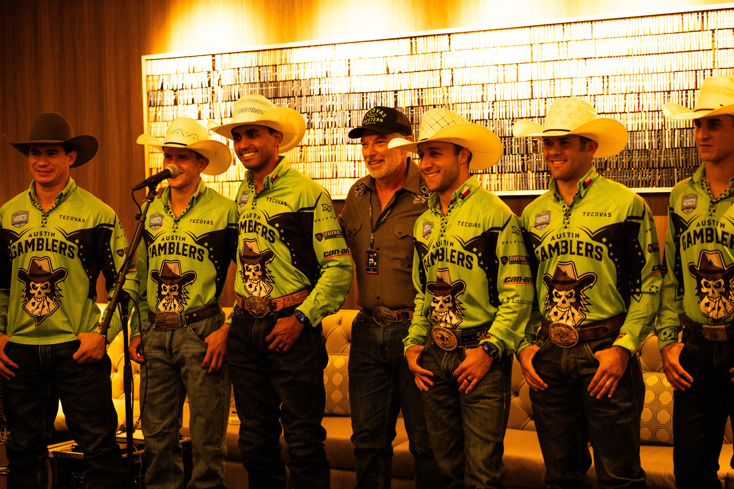Group of men in matching cowboy outfits with hats and logos, standing in a row.