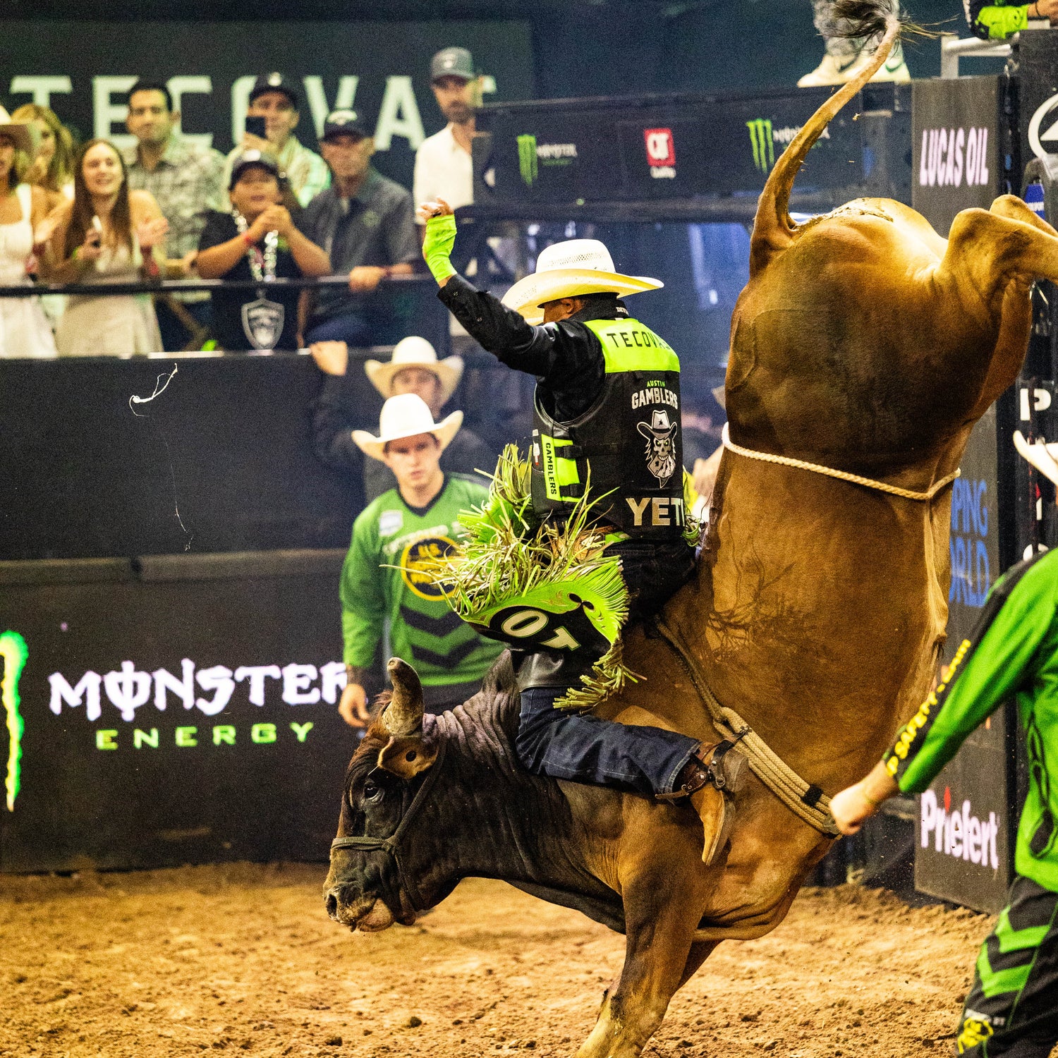 Bull rider in action at a rodeo event with Monster Energy branding.