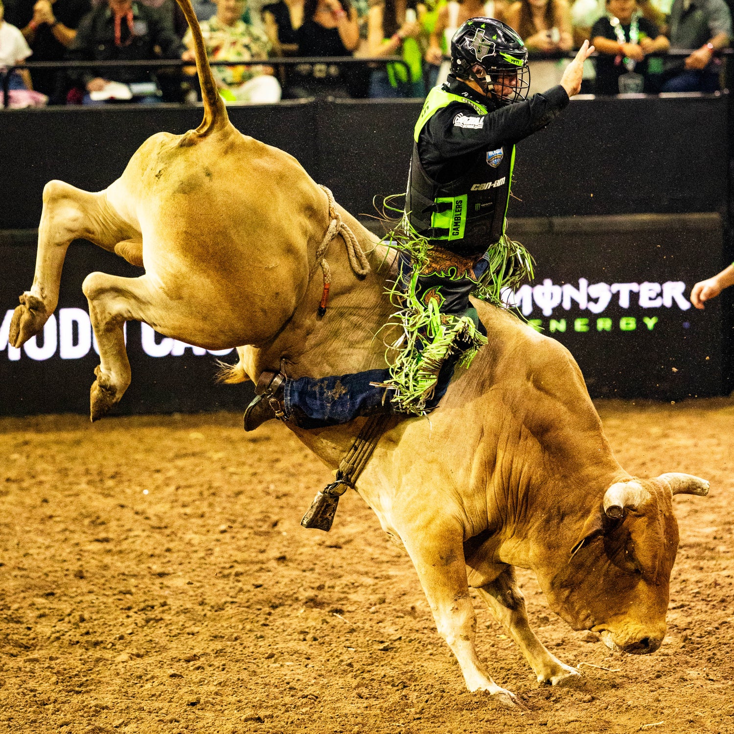 Bull rider on a bucking bull at a rodeo event with a crowd in the background.