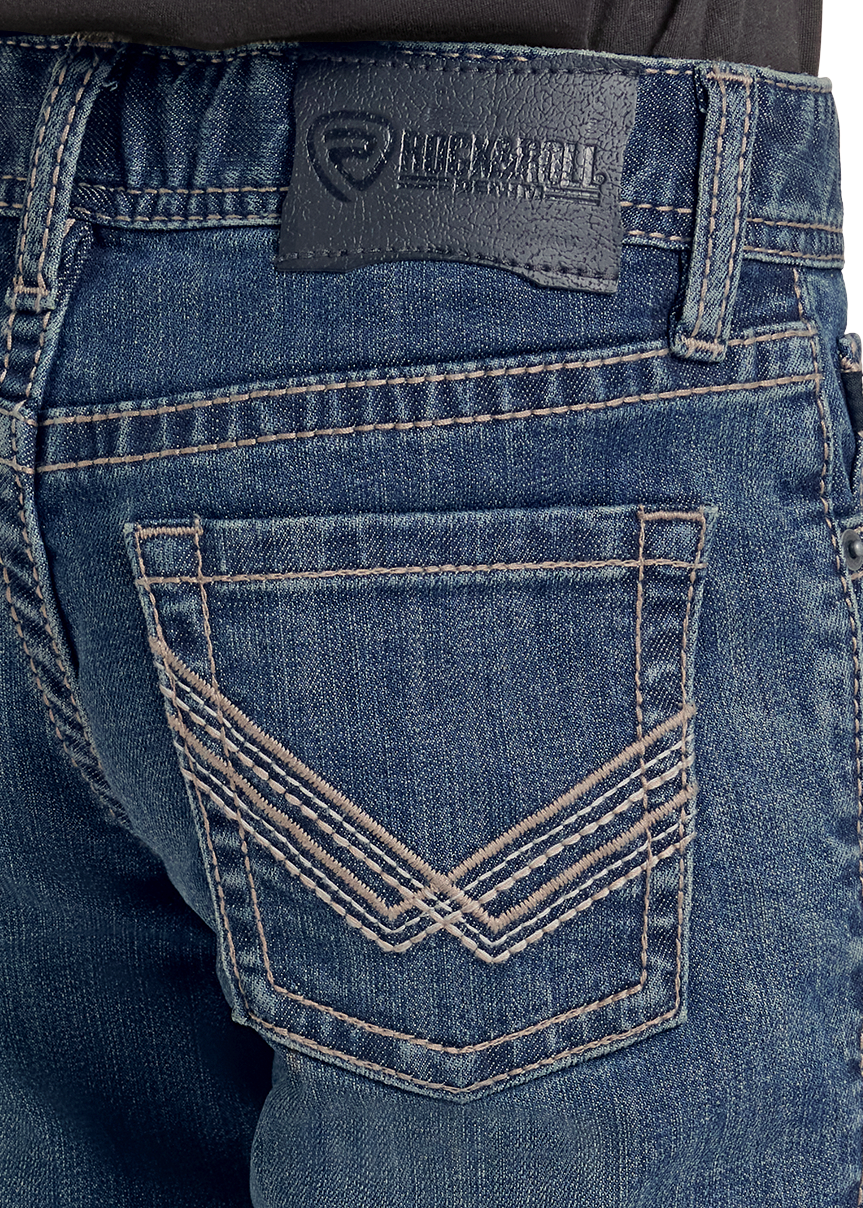 Close-up of the back pocket of blue denim jeans with contrast stitching and a dark leather Rockroll brand patch on the waistband.