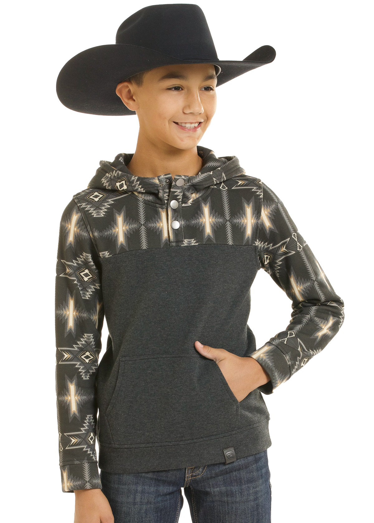 A young boy wearing a black cowboy hat and a dark gray hoodie with a beige geometric pattern on the sleeves and upper chest, paired with blue jeans against a white background.