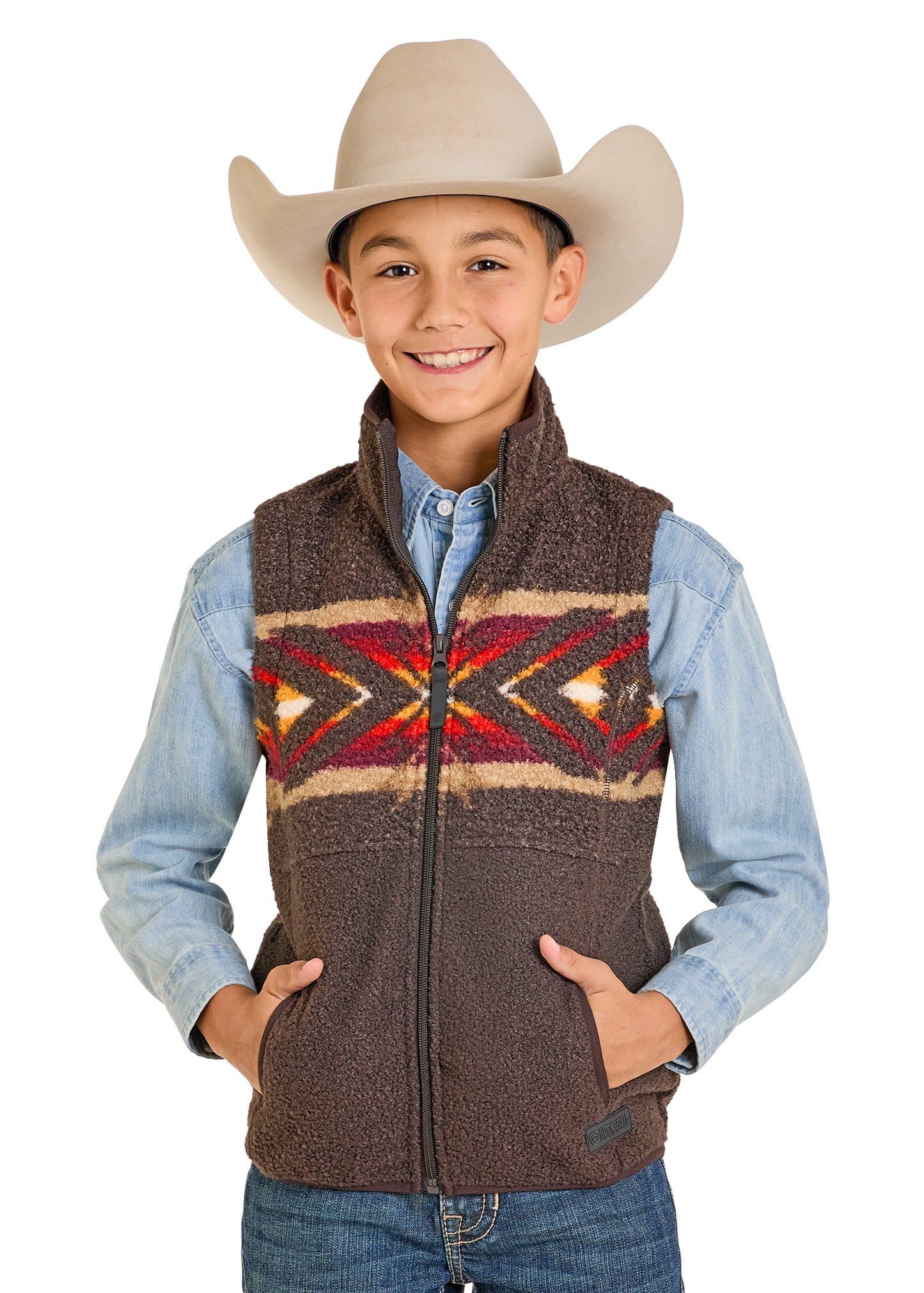 Child wearing a brown vest with a colorful pattern, blue shirt, and cowboy hat on a white background
