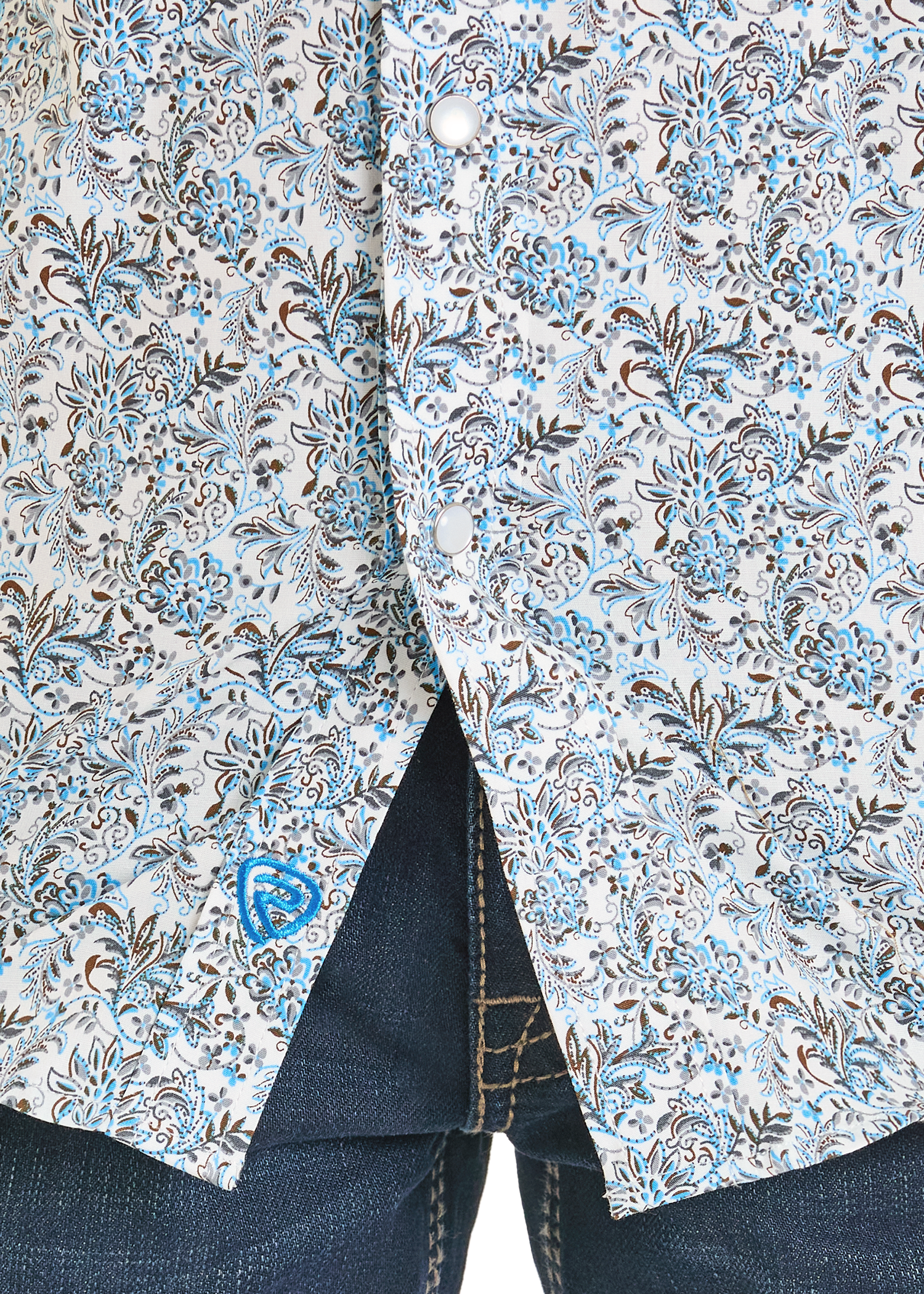 Close-up of a floral patterned shirt with a collar and blue jeans.