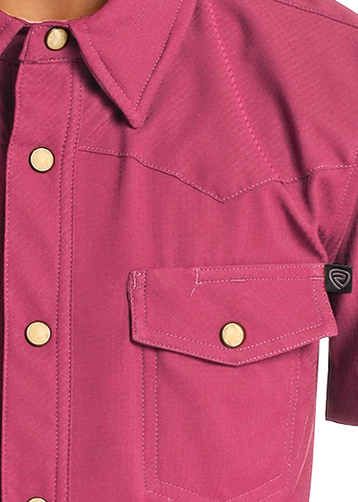 Boy wearing a pink shirt with pearl snaps on a white background
