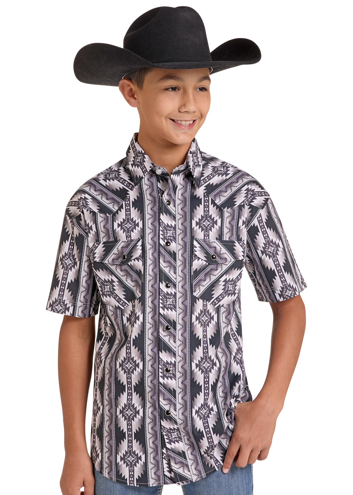 A young boy wearing a black cowboy hat and a short-sleeve button-up shirt with a gray, black, and white geometric southwestern pattern, paired with blue jeans, set against a plain white background.