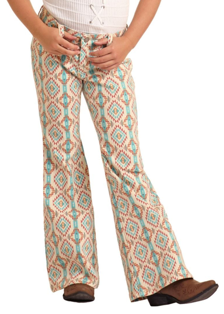 Young girl wearing a white top and patterned pants with a cowboy hat on a white background