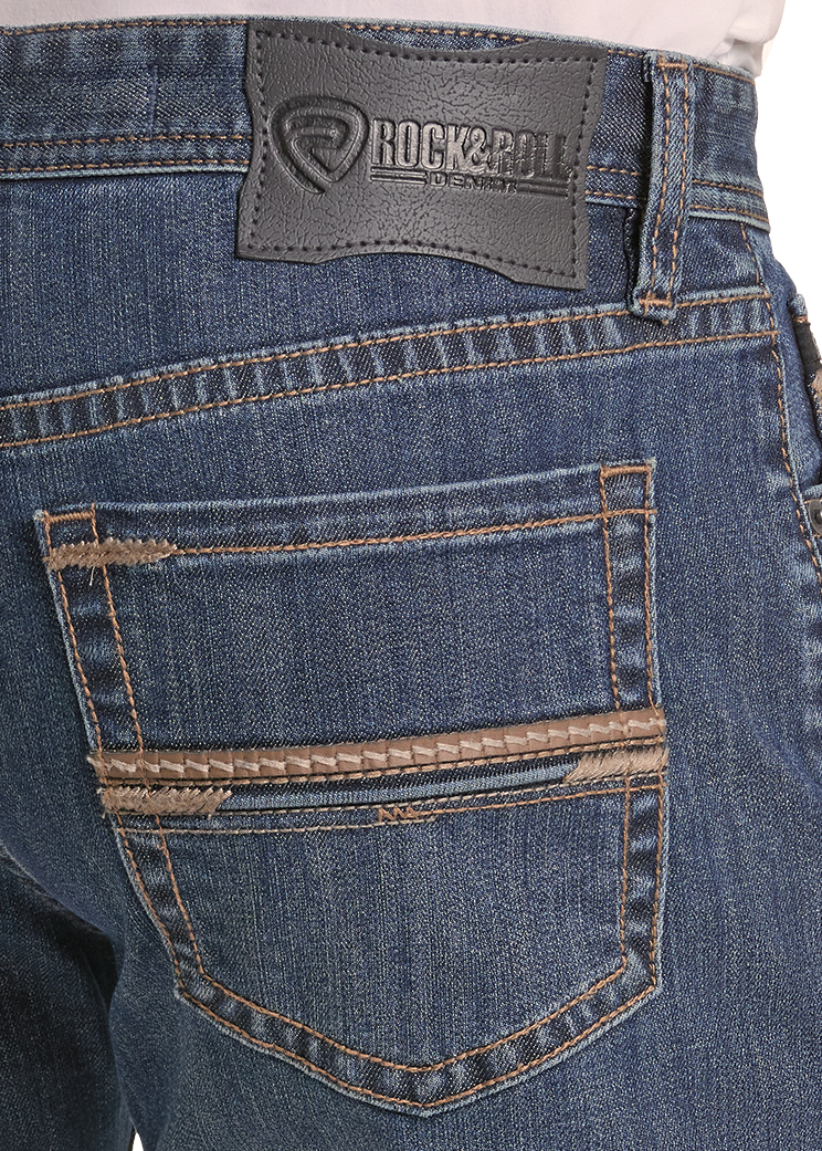 Close-up of the back waistband and back pocket of blue denim jeans, showing a dark gray Rock & Roll brand patch on the waistband and contrast tan stitching.