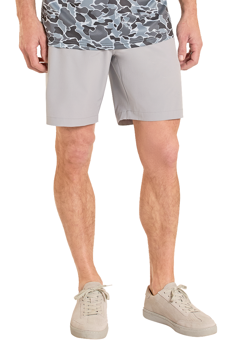 Man wearing a patterned shirt and light shorts on a white background