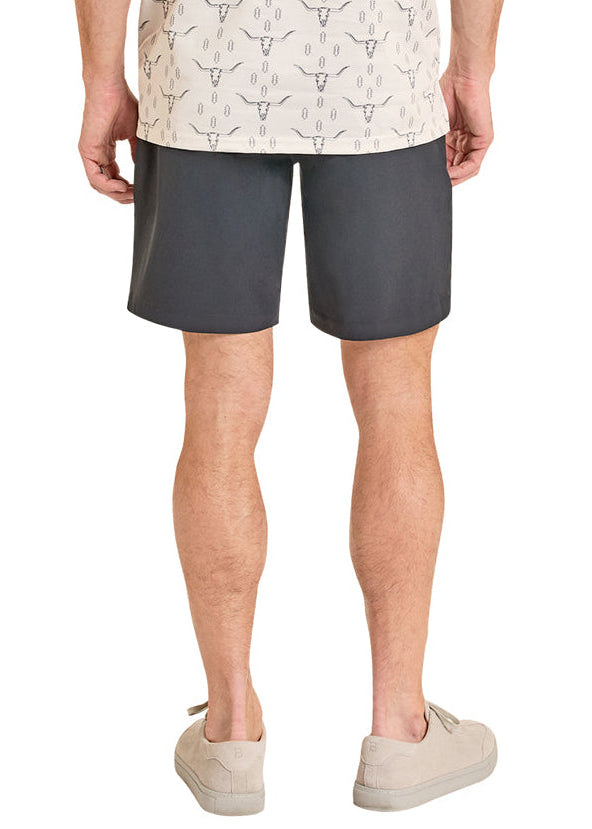 Man wearing a patterned shirt and gray shorts on a white background