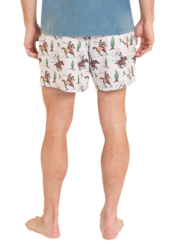 Man wearing a blue t-shirt and patterned shorts on a white background