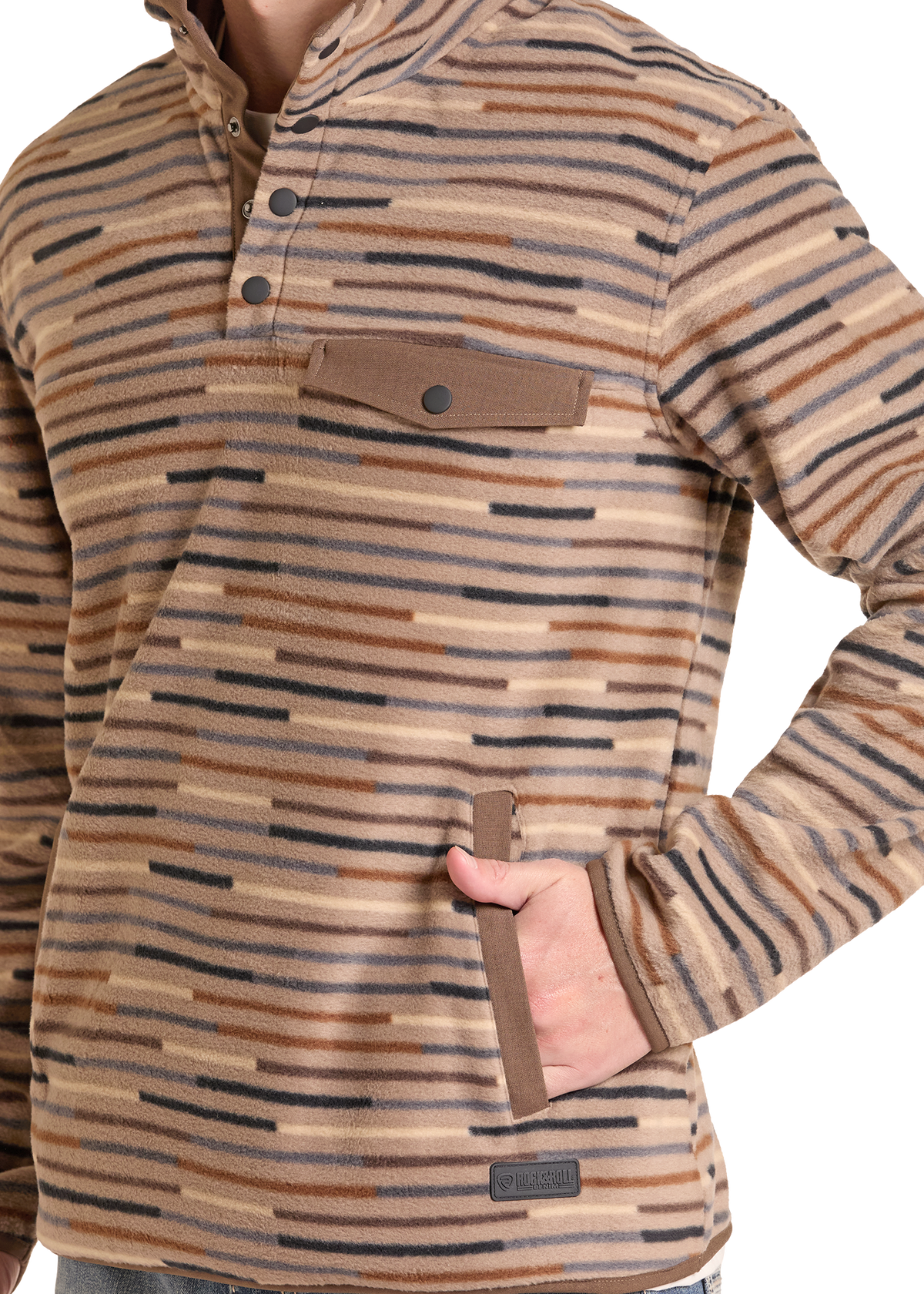 A close-up of a person wearing a long-sleeve quarter-button fleece pullover with horizontal brown, tan, and black stripes. The pullover features a chest pocket with a brown flap and a zippered hand pocket.