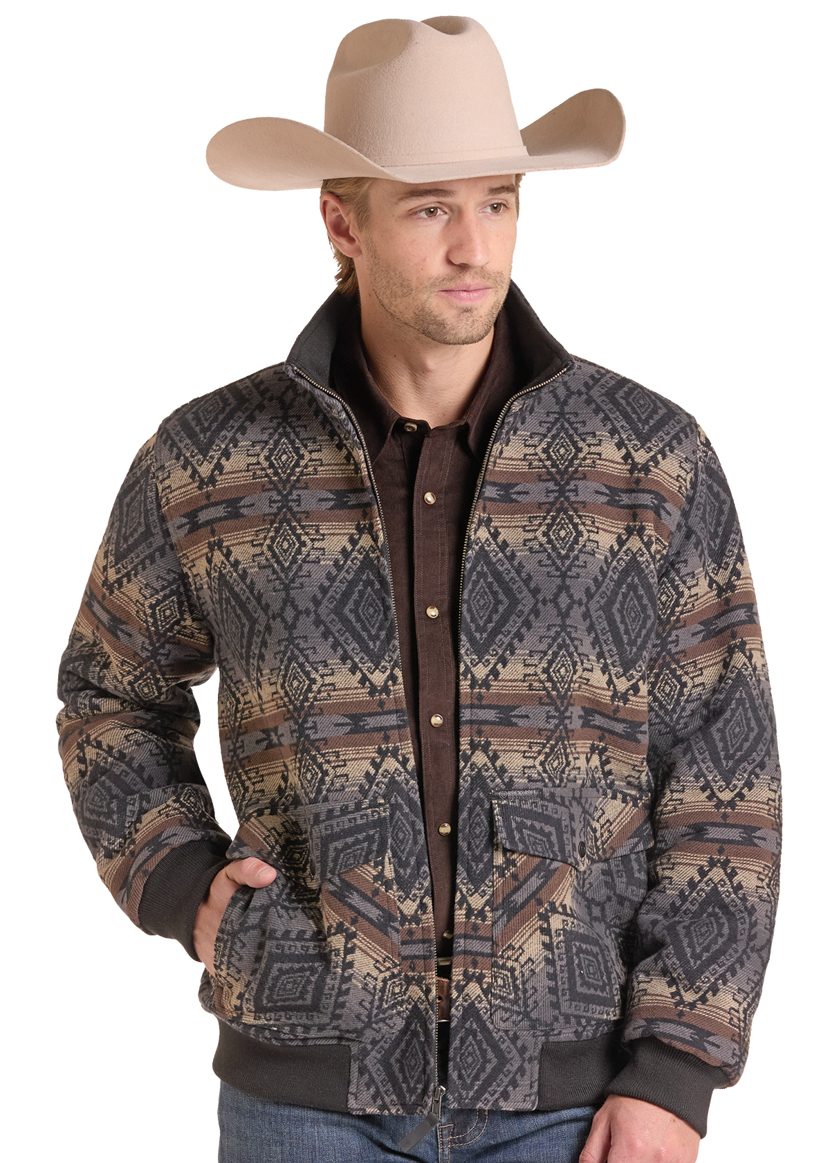 A man wearing a tan cowboy hat and a patterned western-style jacket over a dark brown shirt, photographed against a plain white studio background.