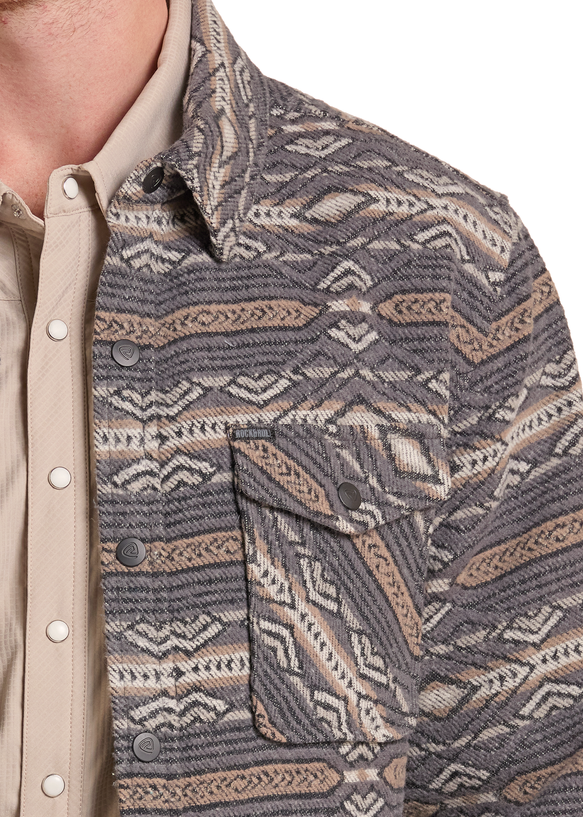 Close-up of a person wearing a patterned button-up shirt jacket over a light beige collared shirt. The jacket has a textured knit western-style pattern in gray, beige, and brown tones with a chest pocket.