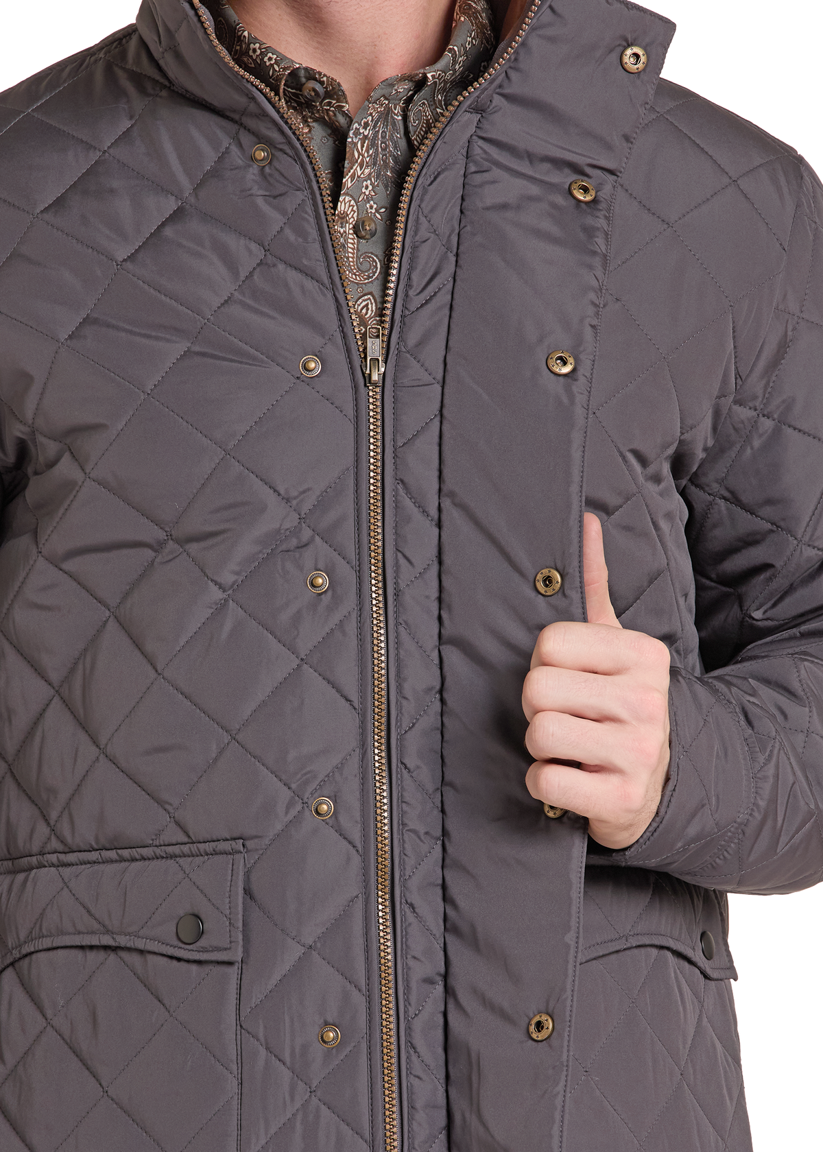 A close-up of a man wearing a dark gray diamond-quilted jacket, showing the texture, gold-tone snaps, and a patterned shirt underneath, with a hand giving a thumbs-up against a white background.