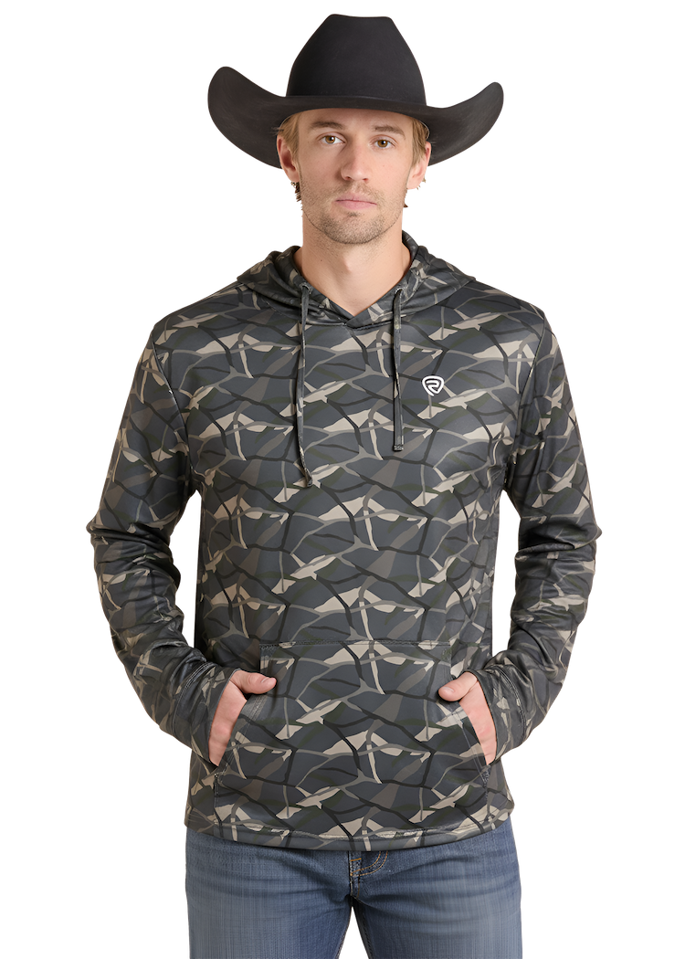 A man wearing a black cowboy hat and a dark camouflage-patterned hoodie with a small white logo on the left chest, paired with blue jeans, against a plain white background.