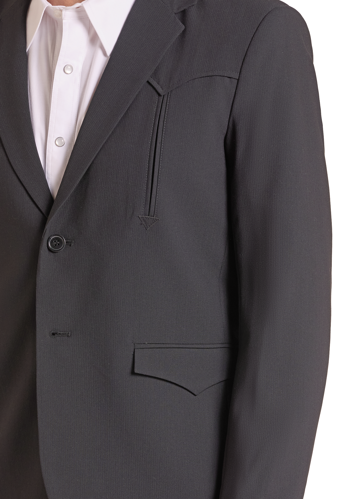 Close-up of a dark charcoal gray suit jacket worn over a white collared dress shirt, showing the lapel, button closure, chest pocket, and front flap pocket.