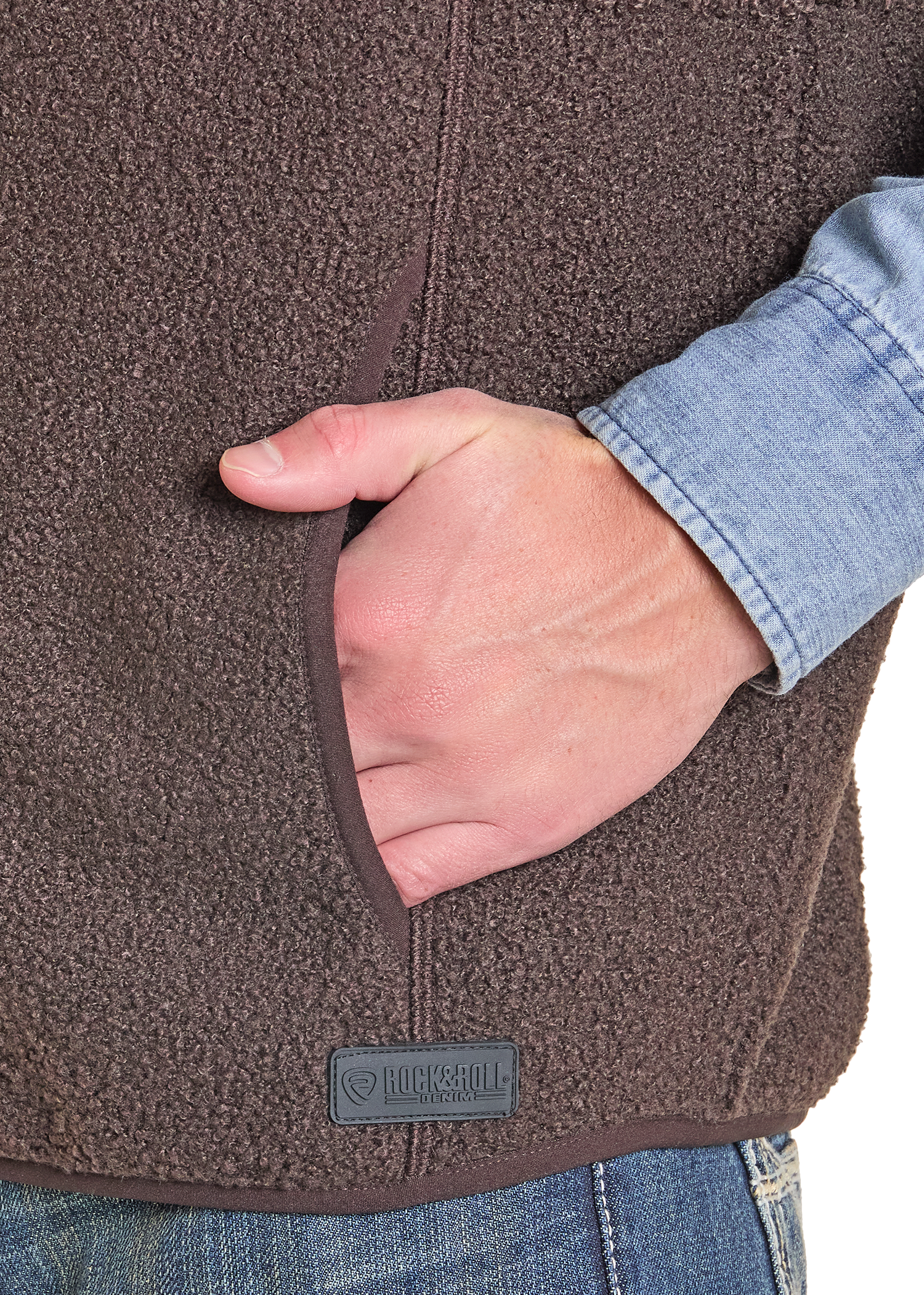 Close-up of a brown fleece jacket with a hand in the pocket, featuring a brand logo.