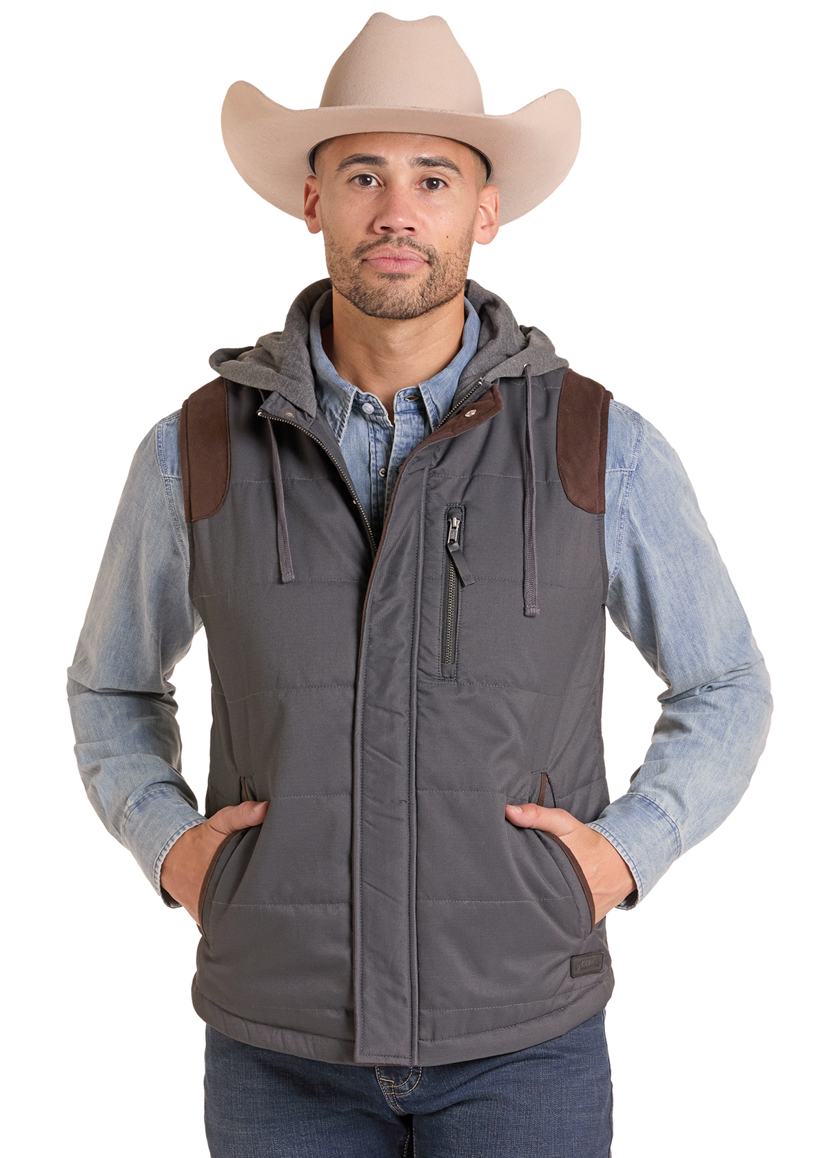 A man wearing a gray hooded puffer vest with brown shoulder patches, a light blue denim shirt, and a beige cowboy hat, photographed against a plain white background.