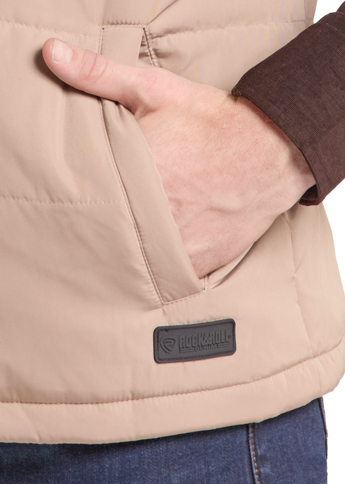 Close-up of a beige puffer vest with a hand in the pocket, showing a black rectangular brand patch that reads 'LUCKSOLD' and a dark brown shirt cuff.