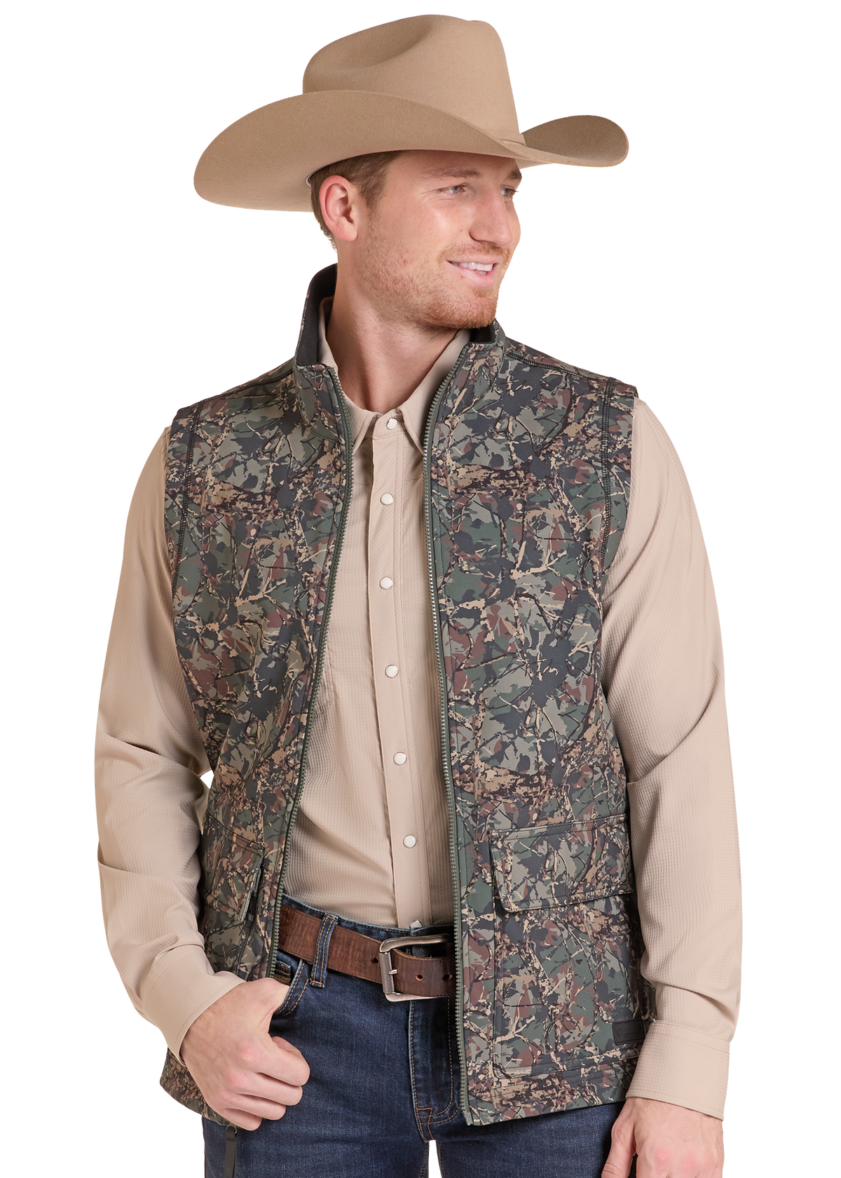 A man wearing a tan cowboy hat, a beige long-sleeve button-up shirt, a brown belt, and a sleeveless camouflage-patterned vest, photographed against a plain white background.