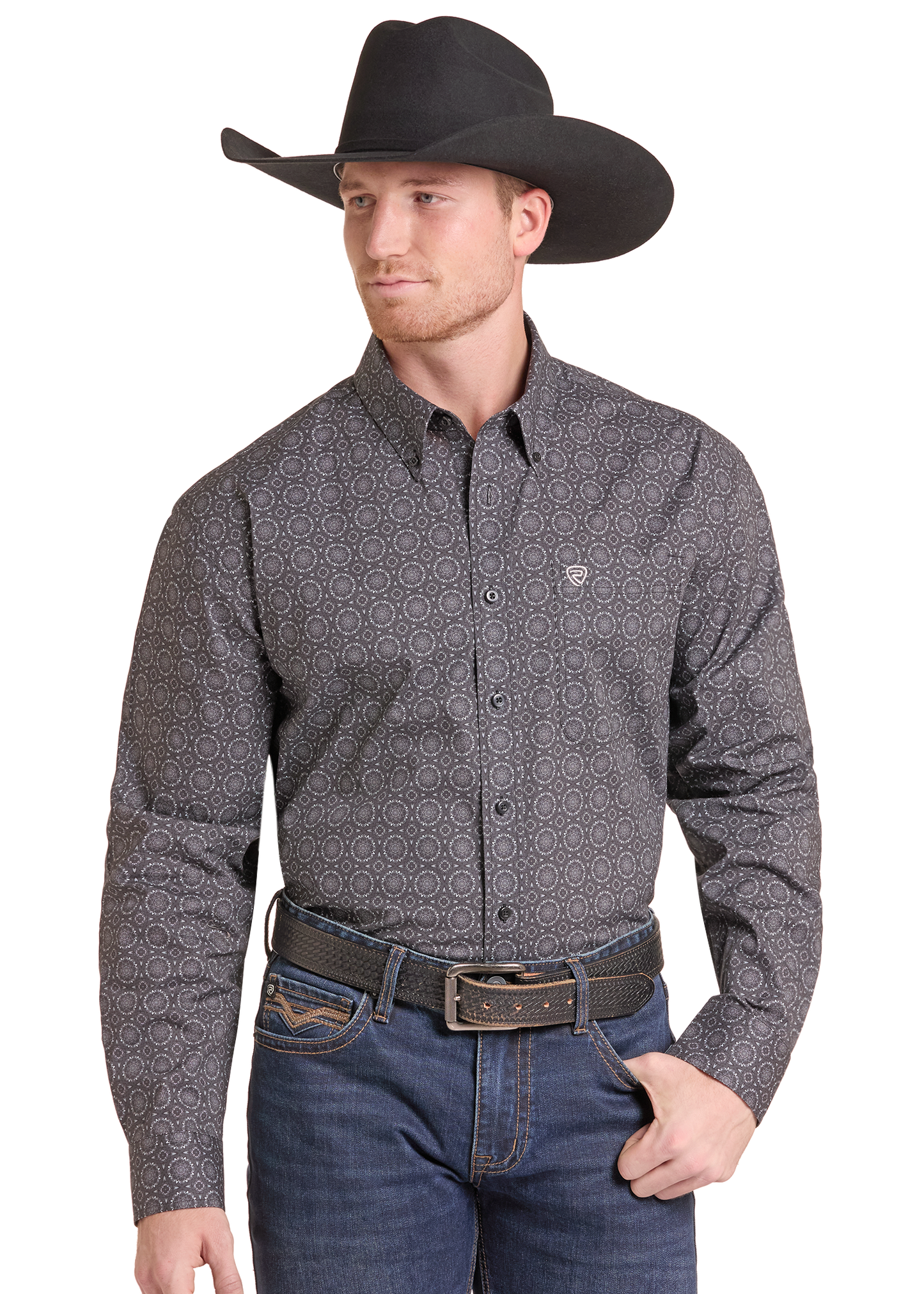 A man wearing a long-sleeve western-style button-down shirt with a small-scale geometric pattern in dark gray and black, paired with a black cowboy hat, brown belt, and blue jeans against a plain white background.
