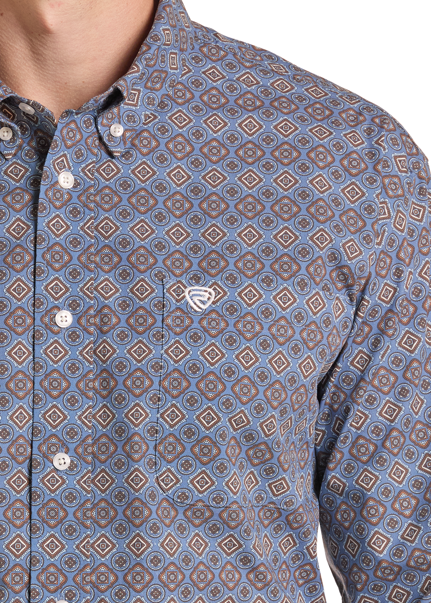 Close-up of a men's button-down shirt featuring an all-over geometric diamond pattern in shades of blue, brown, and beige, with a small white embroidered chest logo.