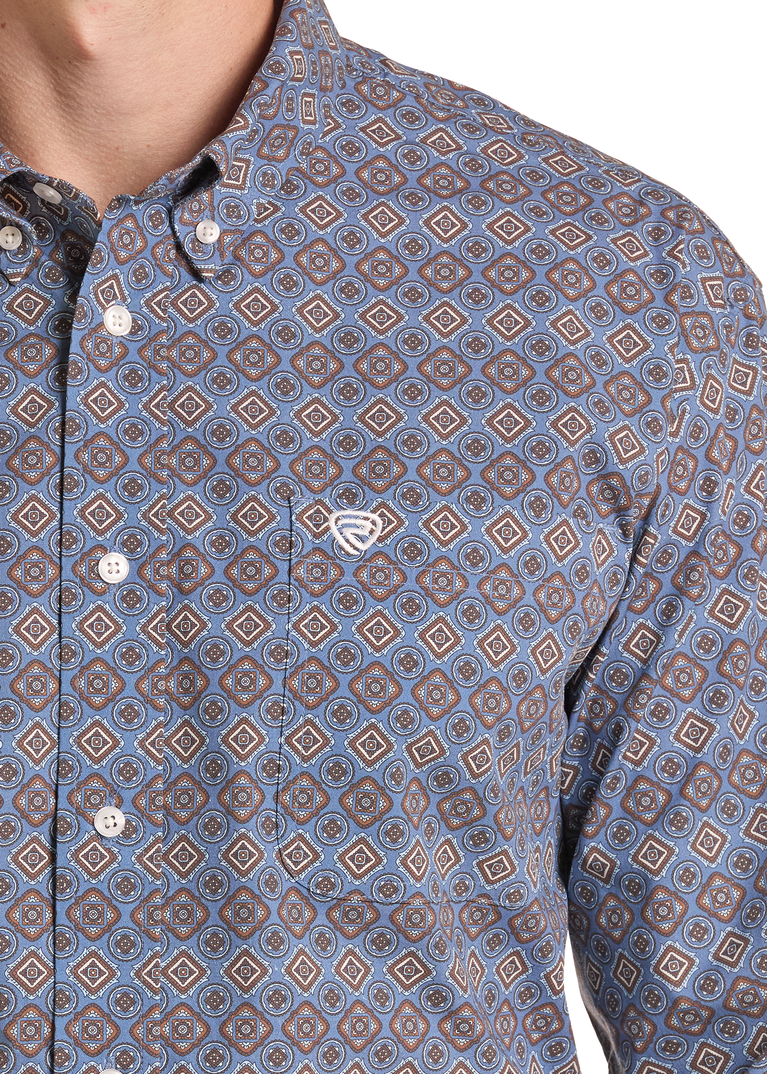 Close-up of a men's button-down shirt featuring an all-over geometric diamond pattern in shades of blue, brown, and beige, with a small white embroidered chest logo.