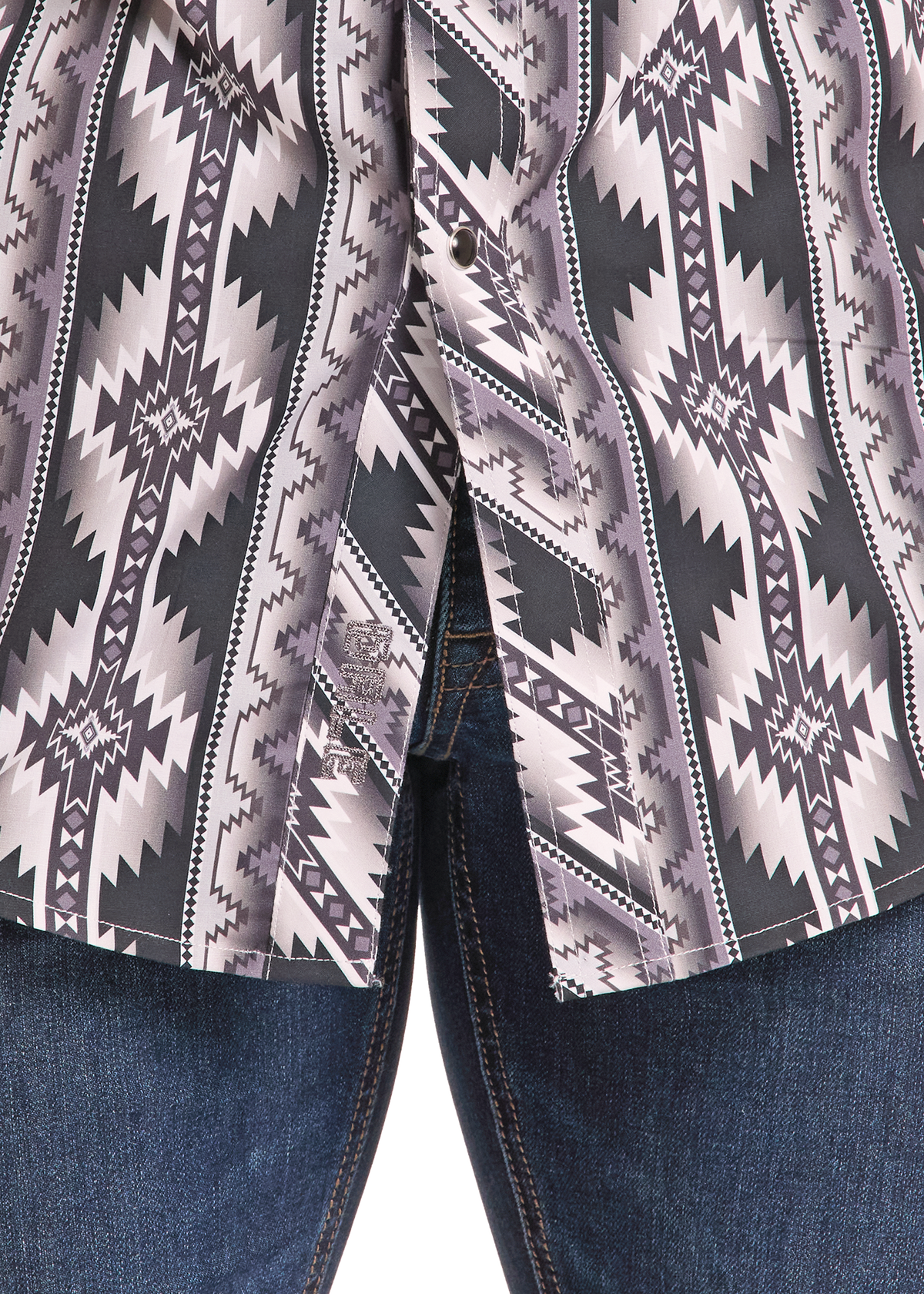 Close-up of a patterned button-up shirt worn with blue jeans. The shirt features a geometric Southwestern-style print in black, gray, and white, with visible buttons and a pointed collar.
