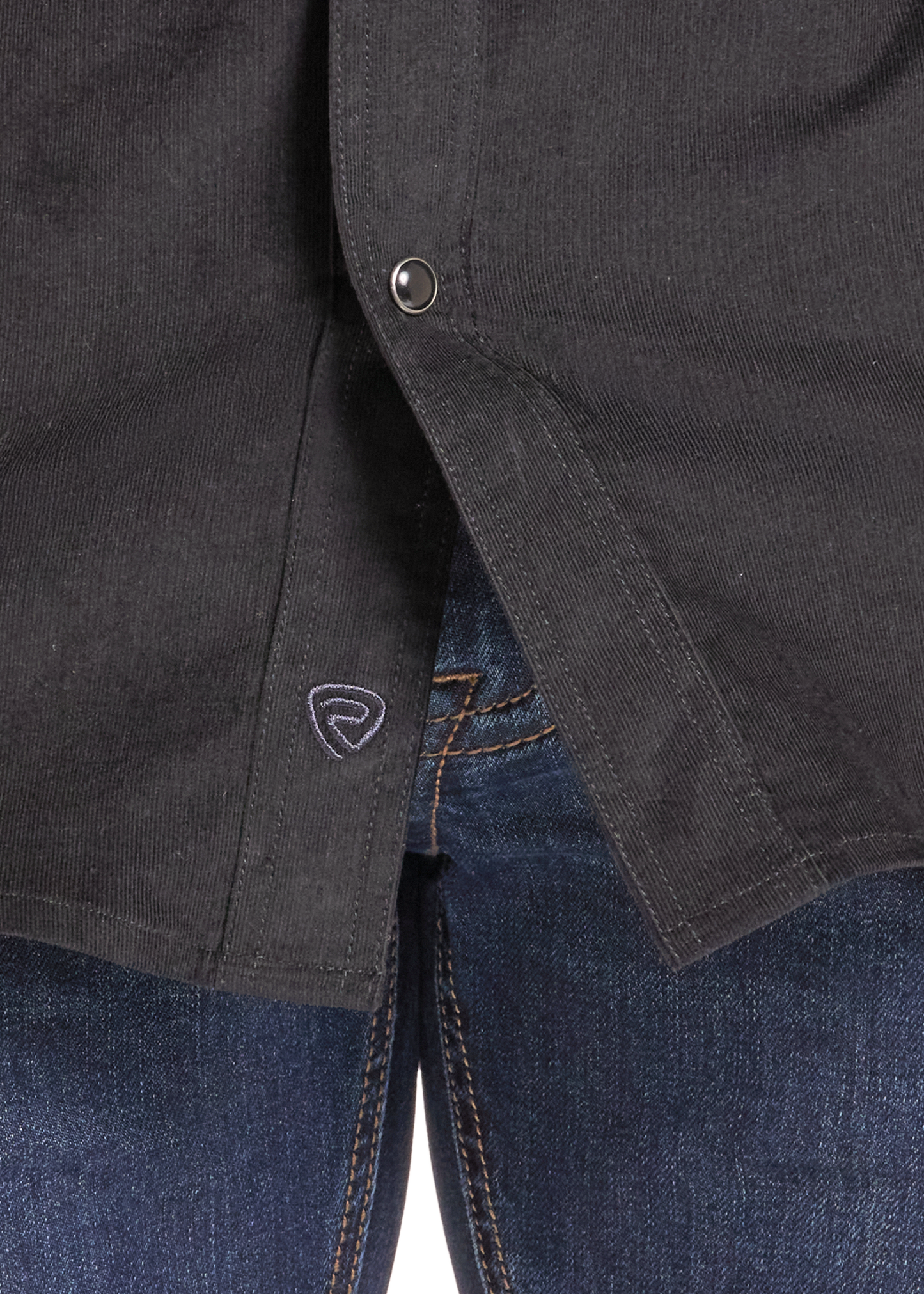 Close-up of a dark charcoal gray button-up shirt worn over blue jeans, showing the button closure and a small shield logo on the shirt pocket.