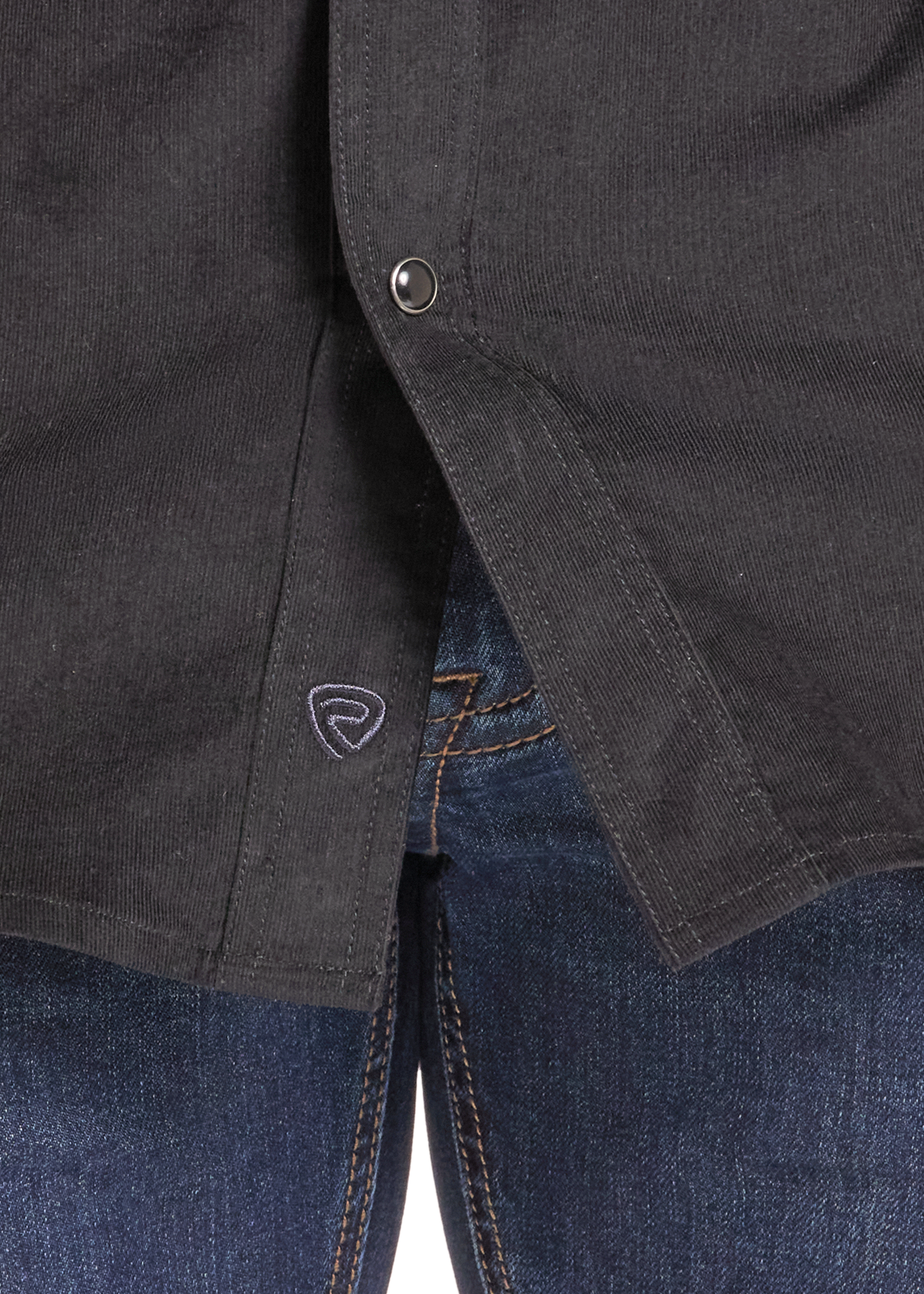 Close-up of a dark charcoal gray button-up shirt worn over blue jeans, showing the button closure and a small shield logo on the shirt pocket.