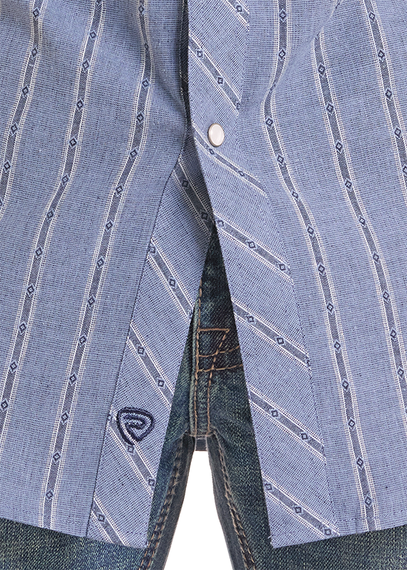 Close-up of a light blue striped button-down shirt worn open over dark blue jeans, showing the fabric pattern and a small embroidered logo near the pocket.