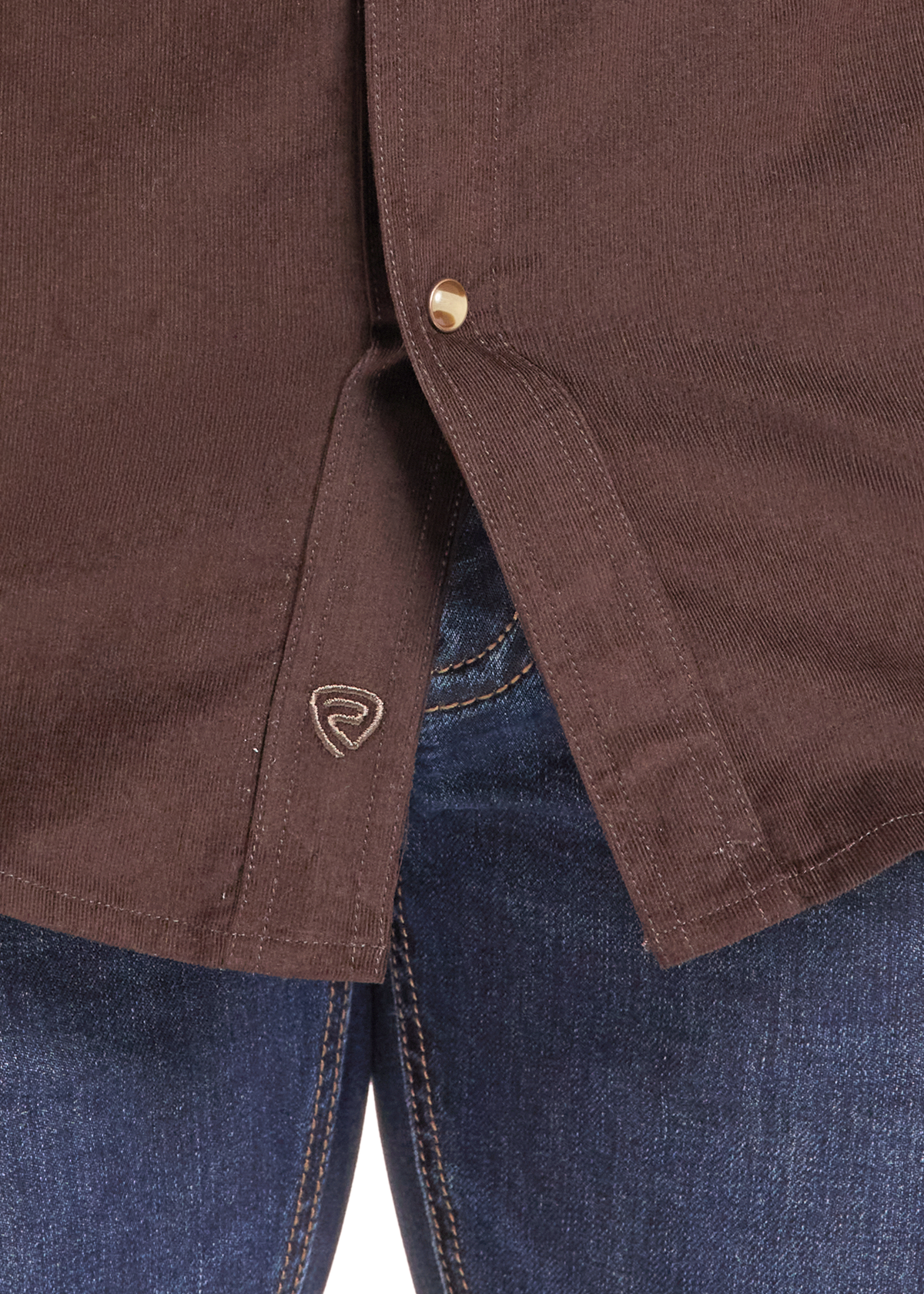 Close-up of a brown button-up shirt worn with blue jeans, showing the brown button, fabric texture, and a small embroidered shield logo near the hem.