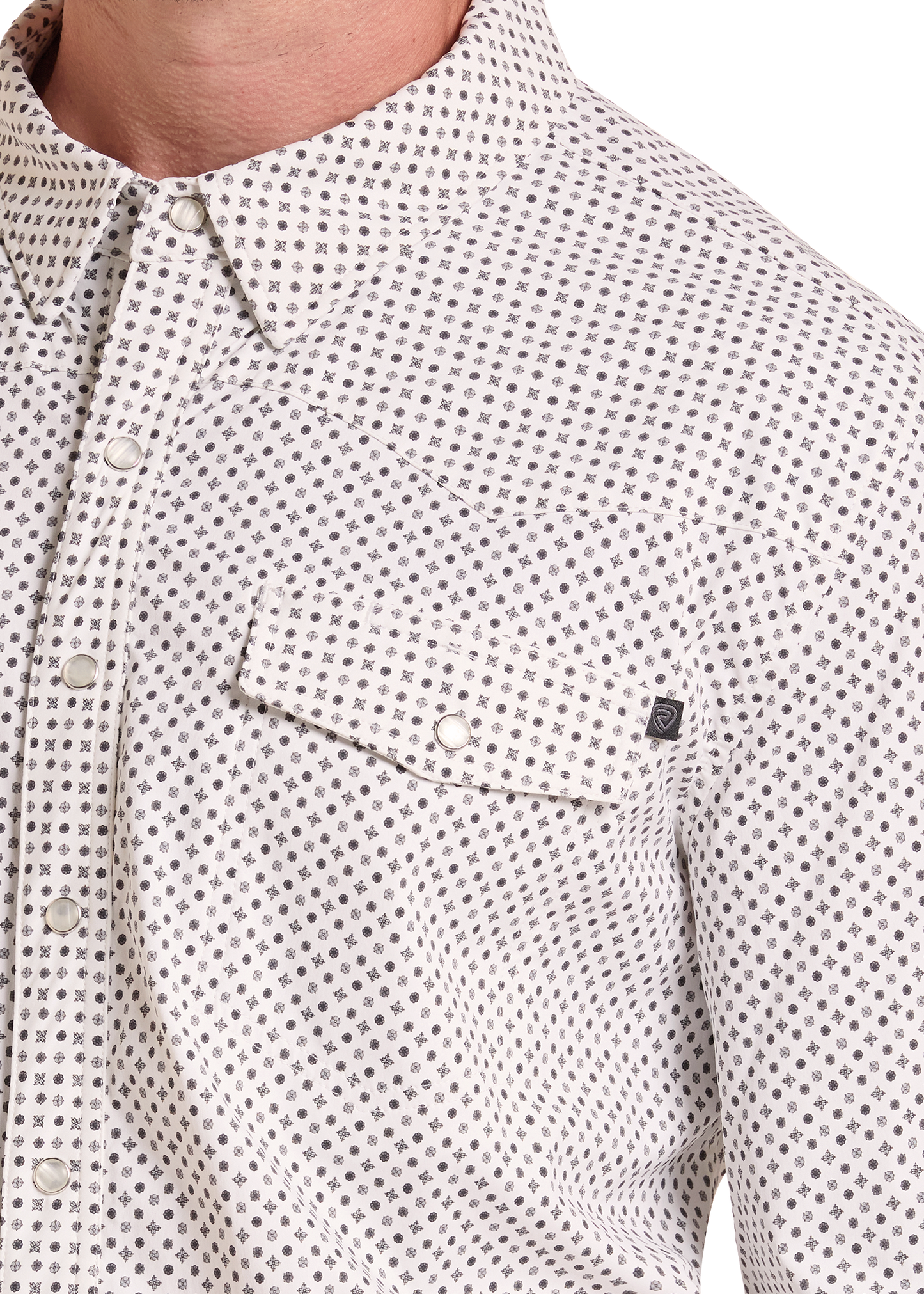 Close-up of a men's button-down shirt with a small repeating geometric dot pattern in gray and black on a white base. The shirt features a pointed collar, a chest pocket with a snap closure, and a small black brand tag on the pocket flap.