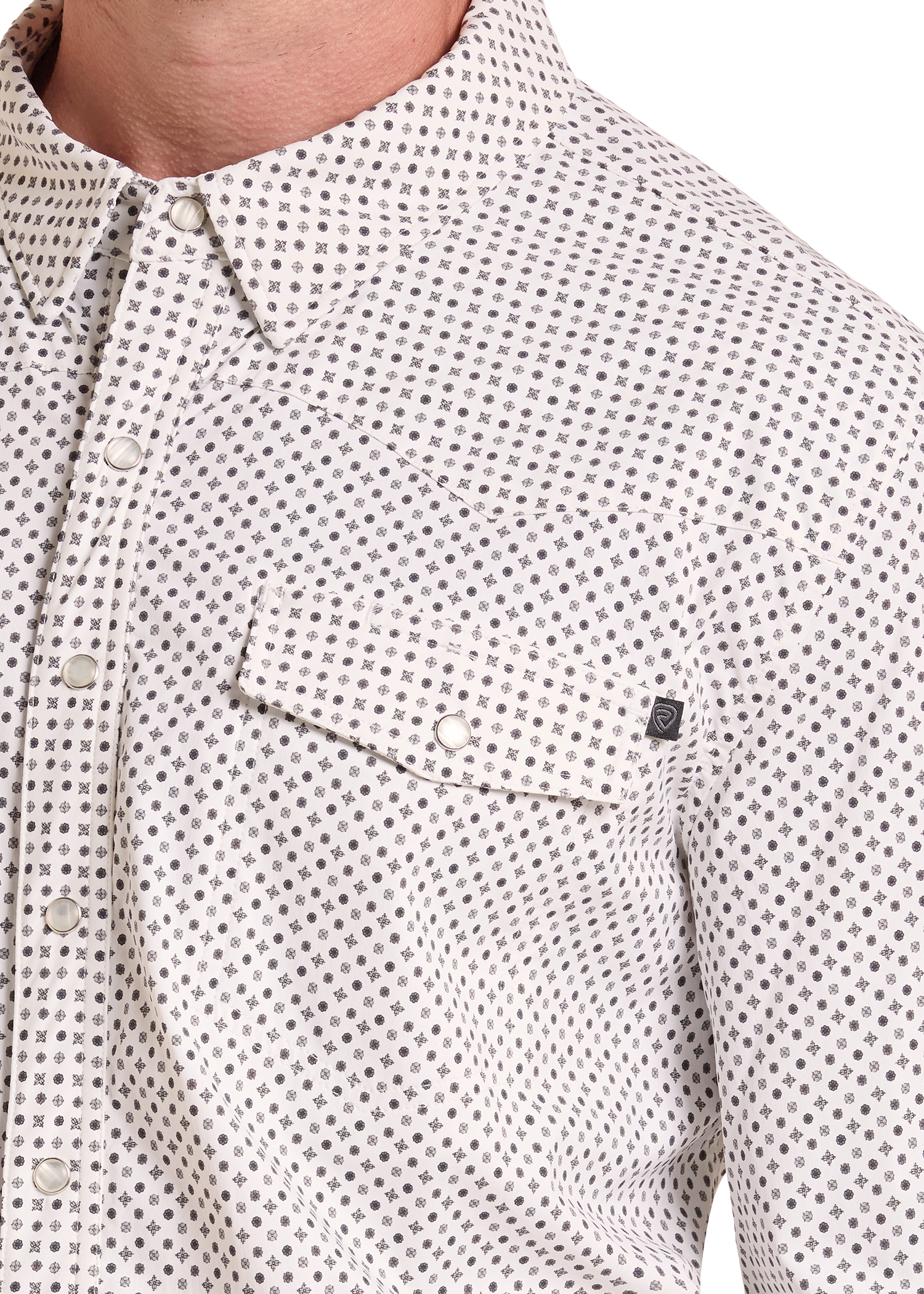 Close-up of a men's button-down shirt with a small repeating geometric dot pattern in gray and black on a white base. The shirt features a pointed collar, a chest pocket with a snap closure, and a small black brand tag on the pocket flap.