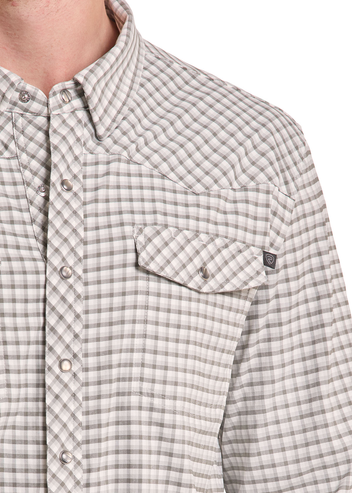 Close-up of a man wearing a long-sleeve button-up shirt with a gray and beige gingham plaid pattern, featuring a chest pocket and snap buttons.