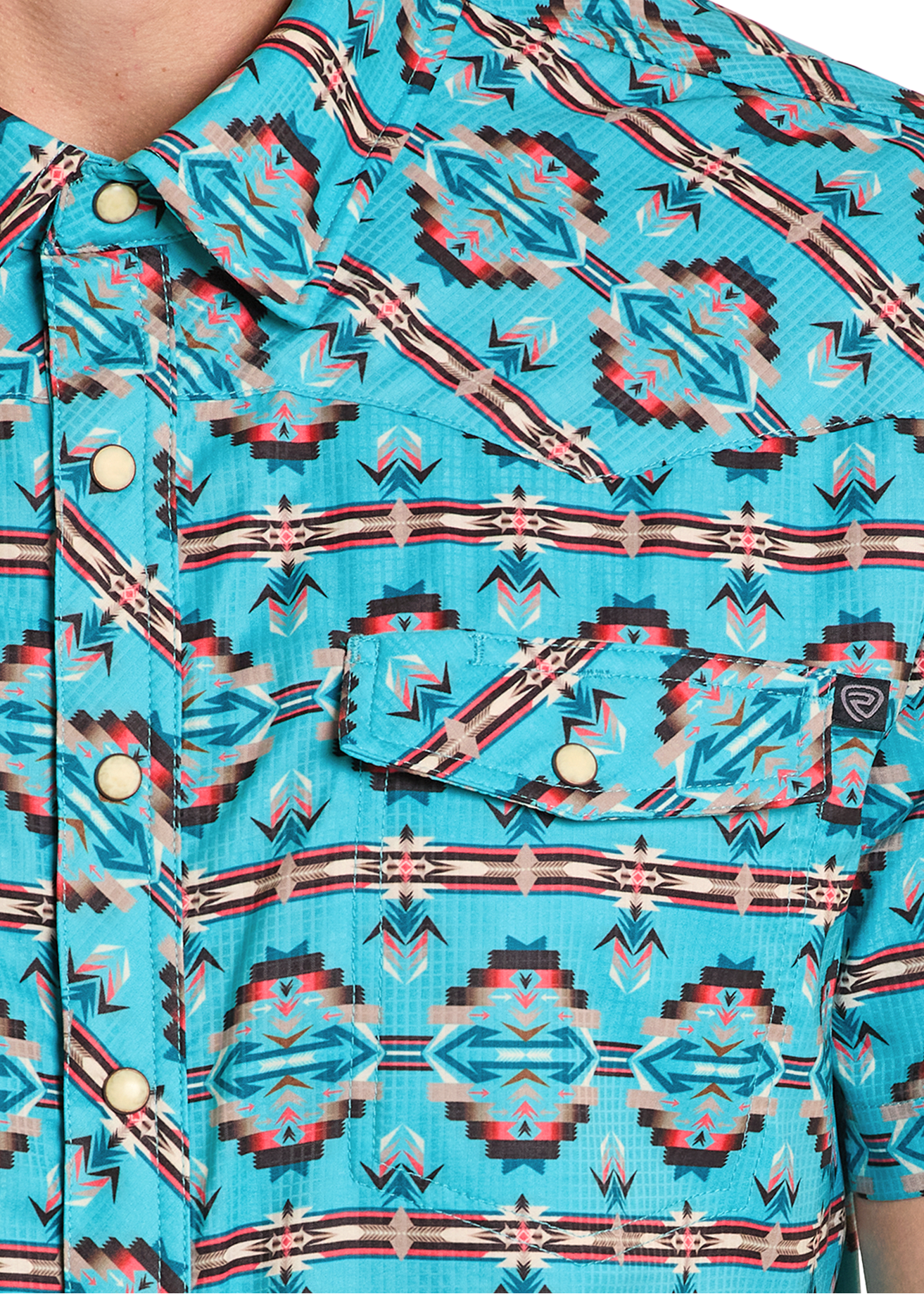 Close-up of a turquoise patterned shirt with visible branding.