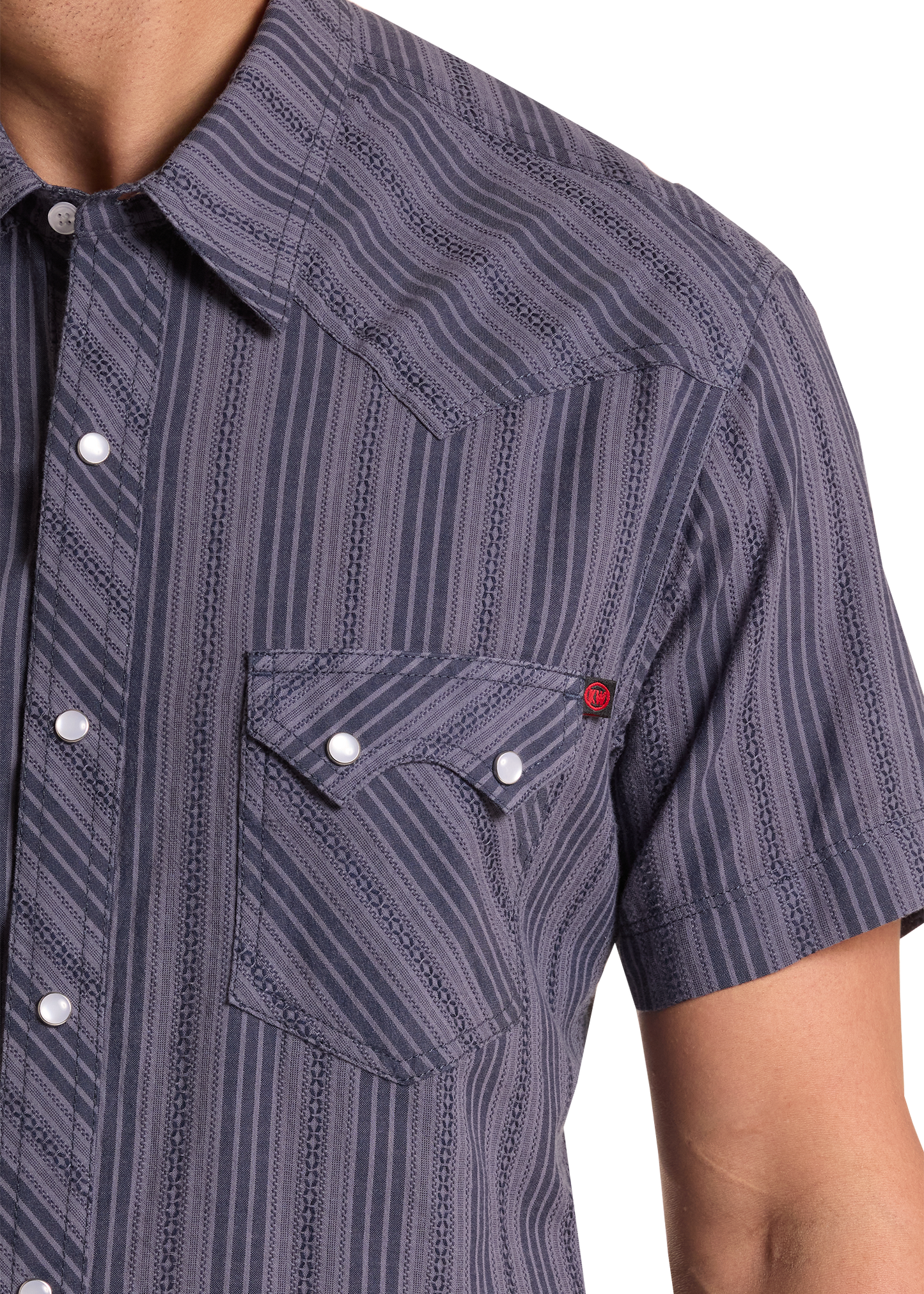 Close-up of a person wearing a patterned short-sleeve shirt with a pocket and buttons.