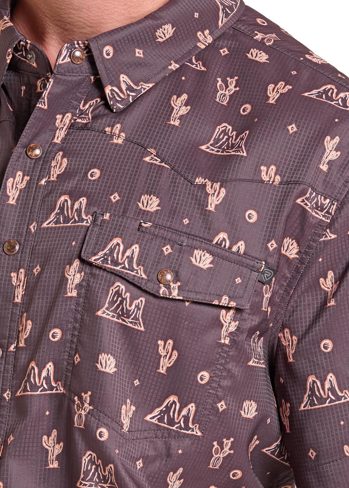 Close-up of a men's button-down shirt with a dark brown base and a light tan desert pattern featuring cacti, mountains, and geometric shapes.