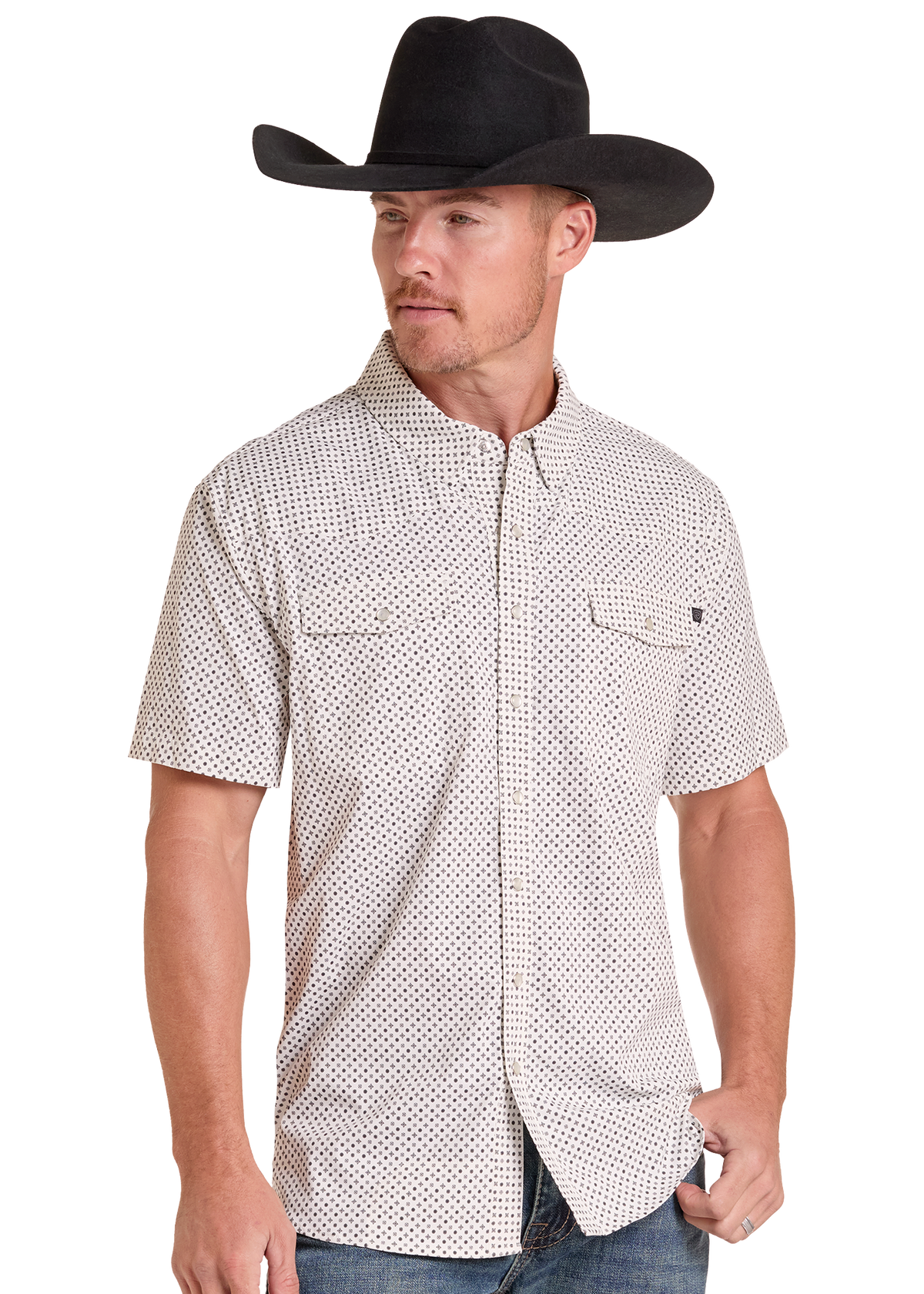A man wearing a black cowboy hat and a short-sleeve button-up shirt with a small black-on-white geometric pattern, paired with blue jeans, photographed against a plain white background.