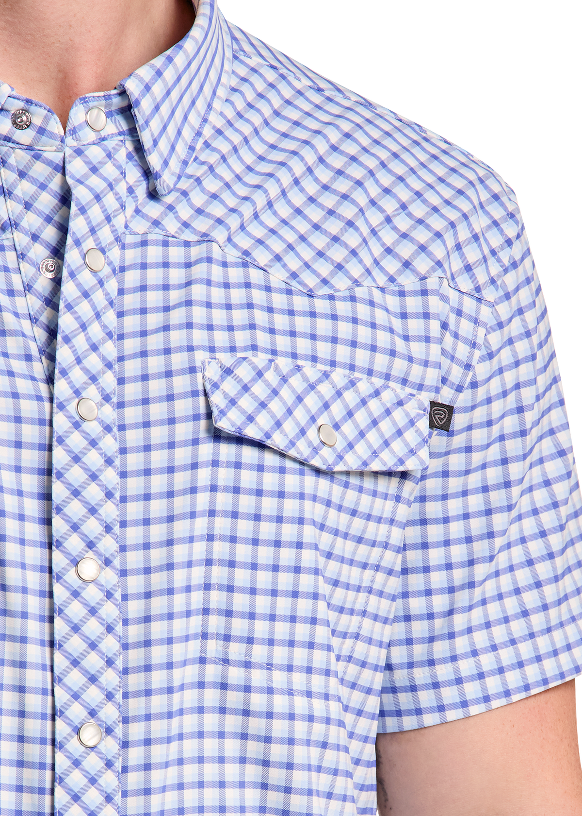 Close-up of a man wearing a short-sleeve button-up shirt with a blue and white gingham check pattern, featuring a chest pocket with a button flap.