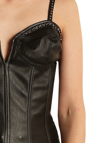 Woman wearing a black leather corset top and blue jeans with a beige cowboy hat on a white background