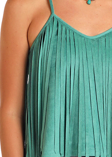 Woman wearing a green fringe top and light blue jeans with a beige cowboy hat on a white background