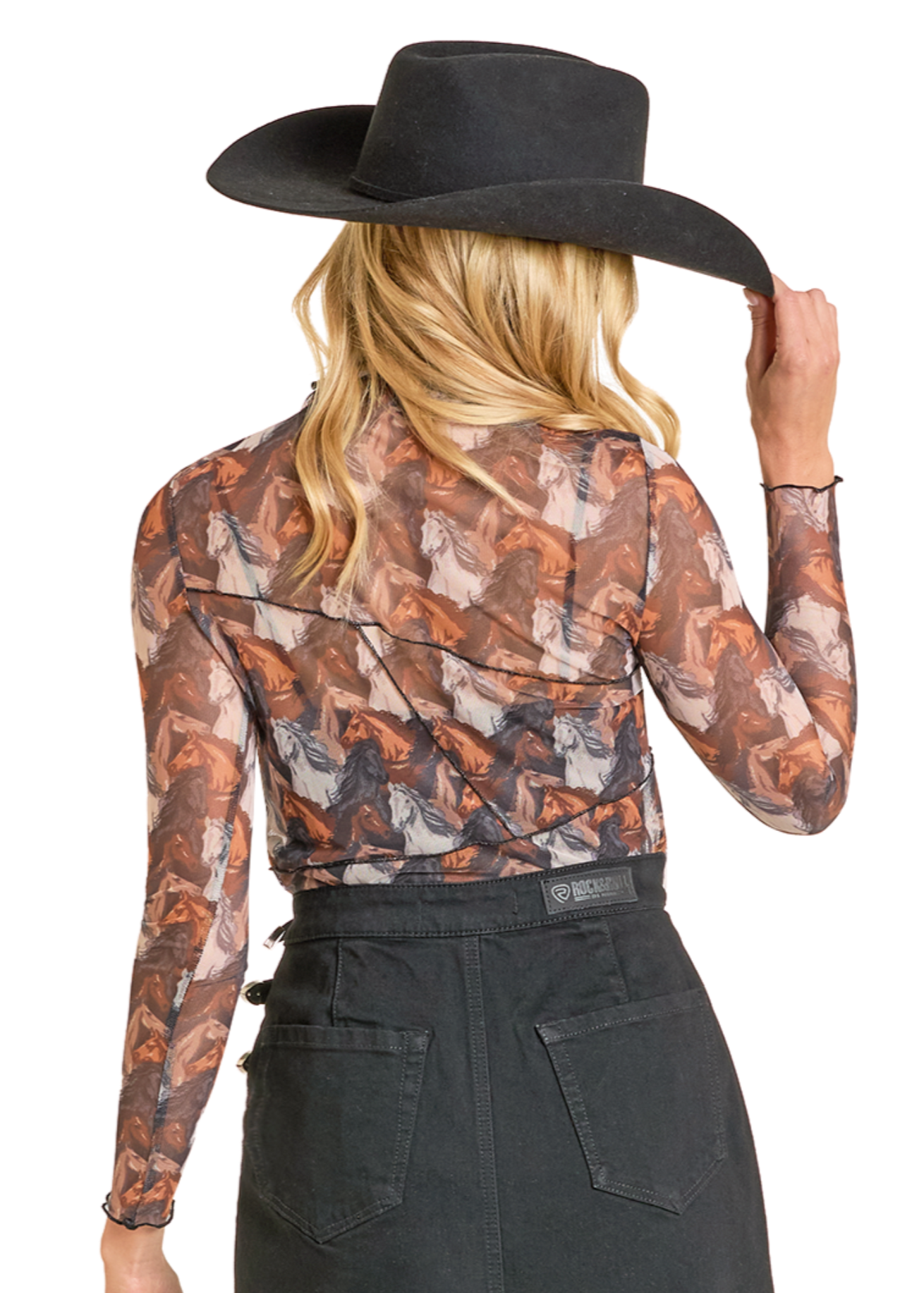 Person wearing a patterned blouse and black skirt with a cowboy hat on a white background