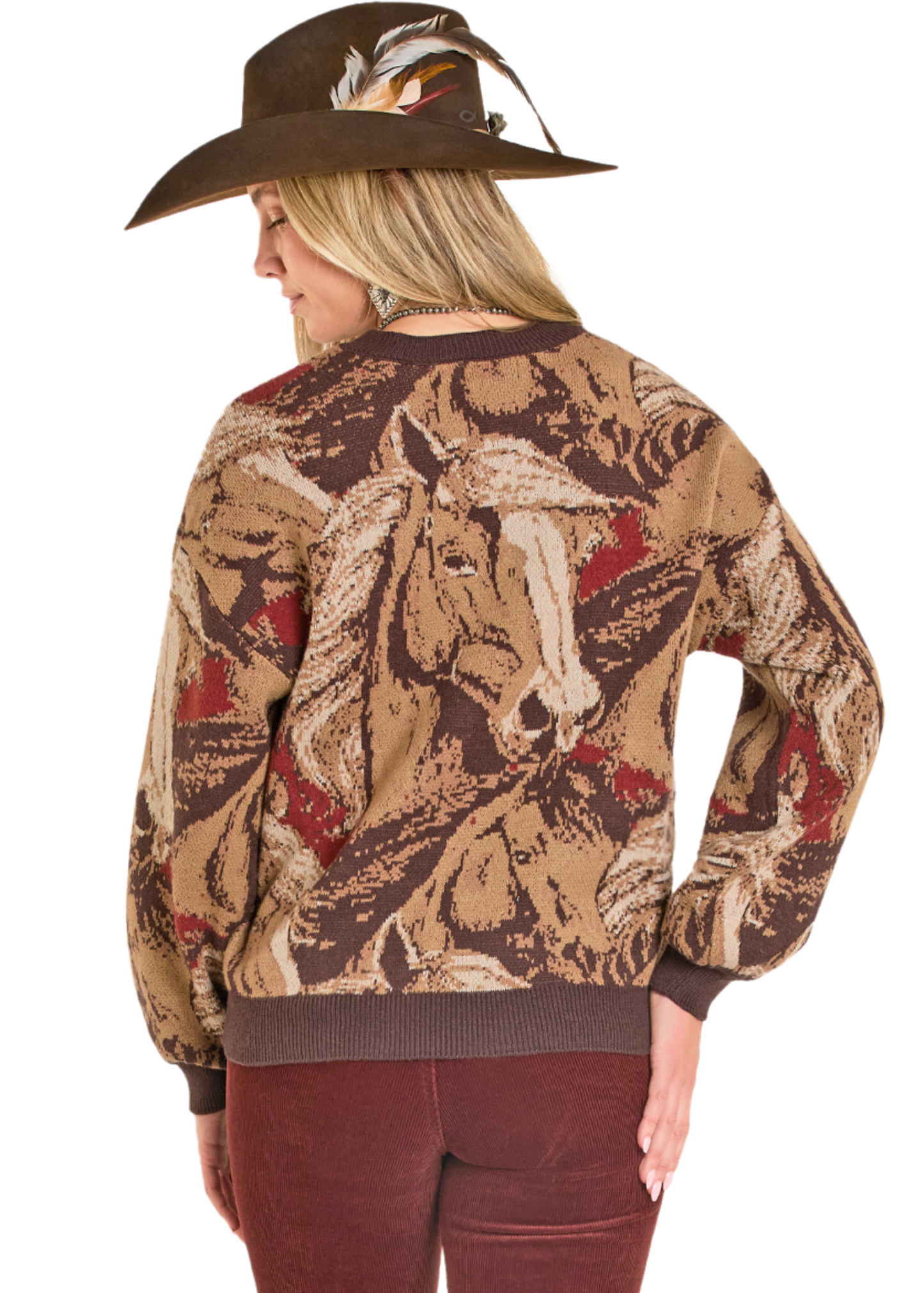 Woman wearing a patterned sweater with horse design and a cowboy hat.
