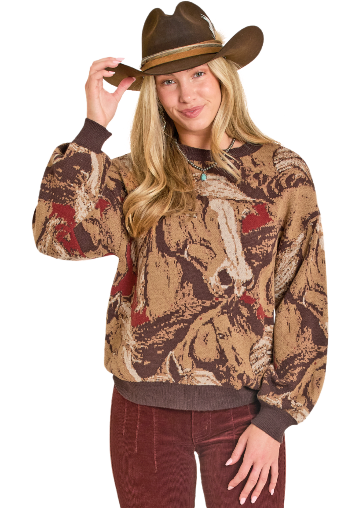 Person wearing a patterned sweater with horse design and a cowboy hat on a white background