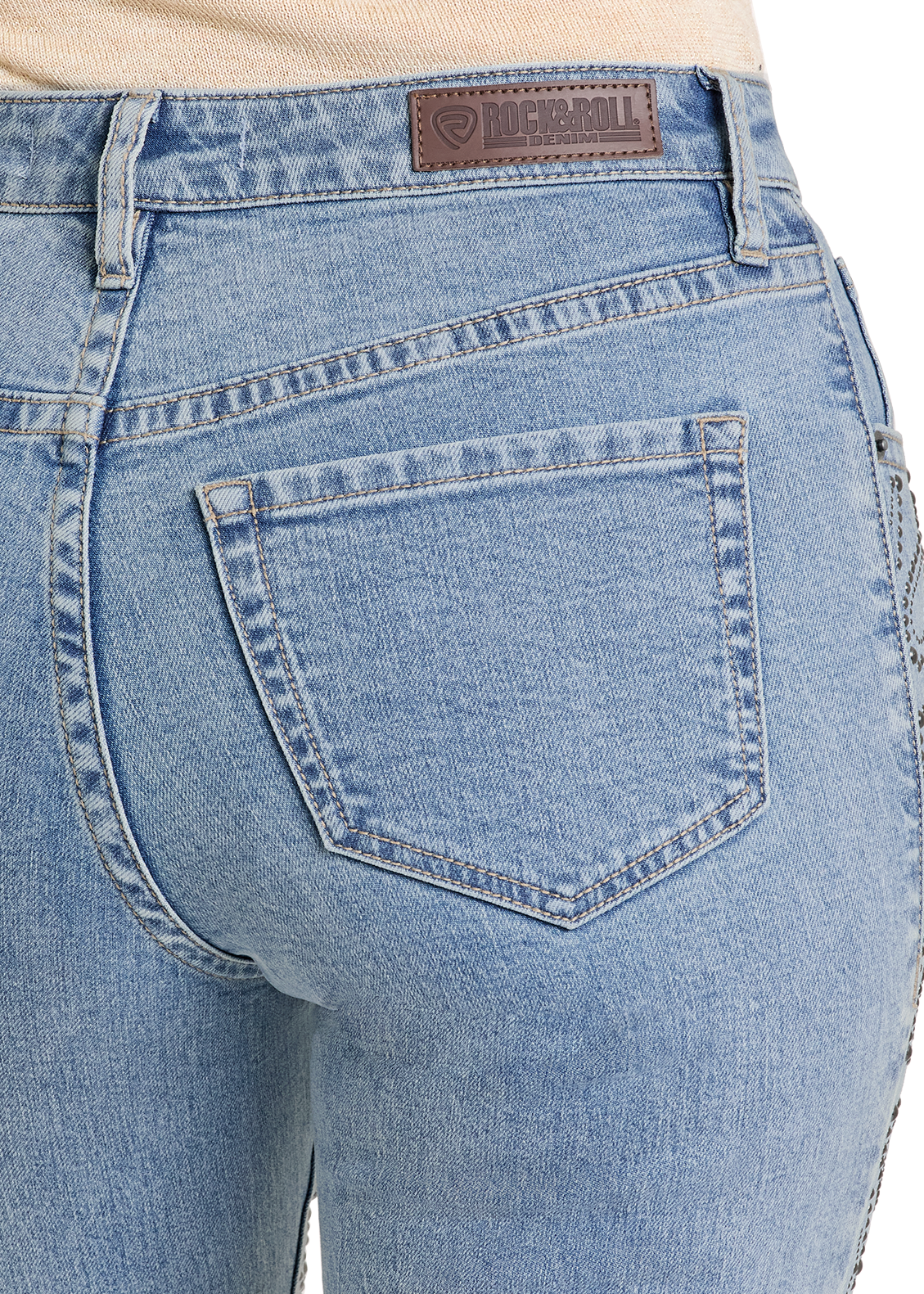 Close up of light blue jeans worn by a person on a white background